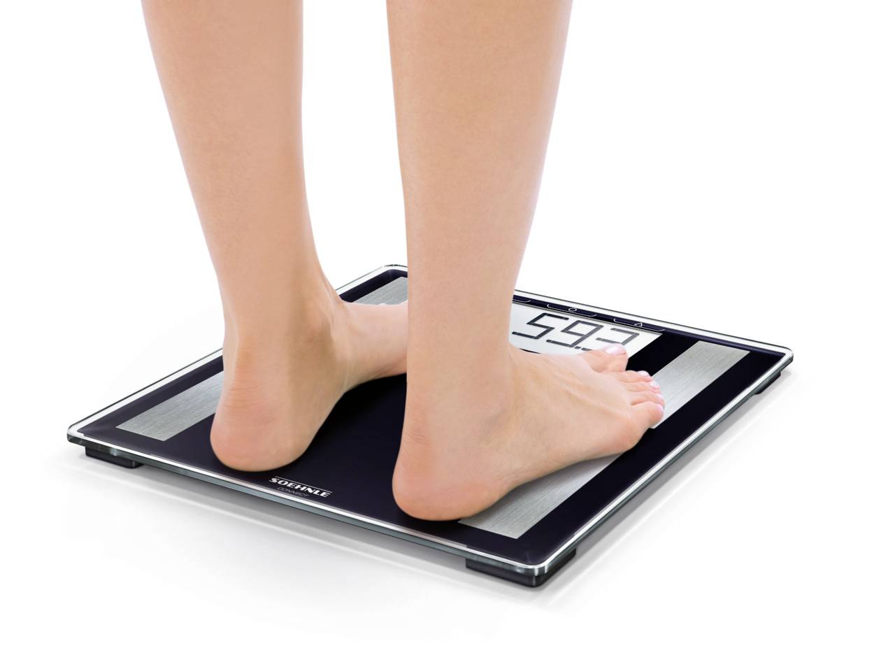 Eine Person steht barfuß auf einer digitalen Waage. Das Display zeigt das Gewicht in Kilogramm an.