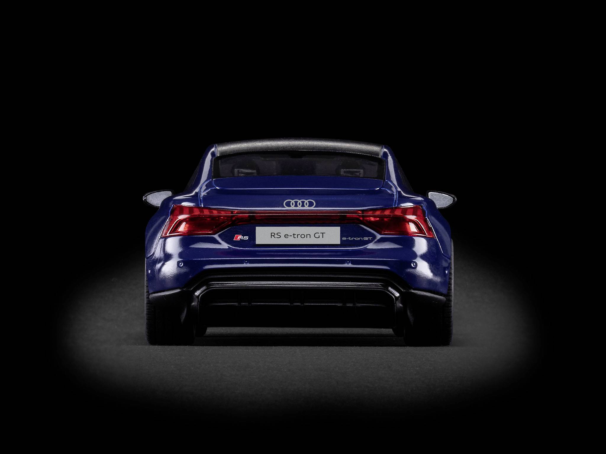 Rückansicht eines blauen Audi RS e-tron GT auf schwarzem Hintergrund, zeigt das Firmenlogo und Details der Rücklichter.
