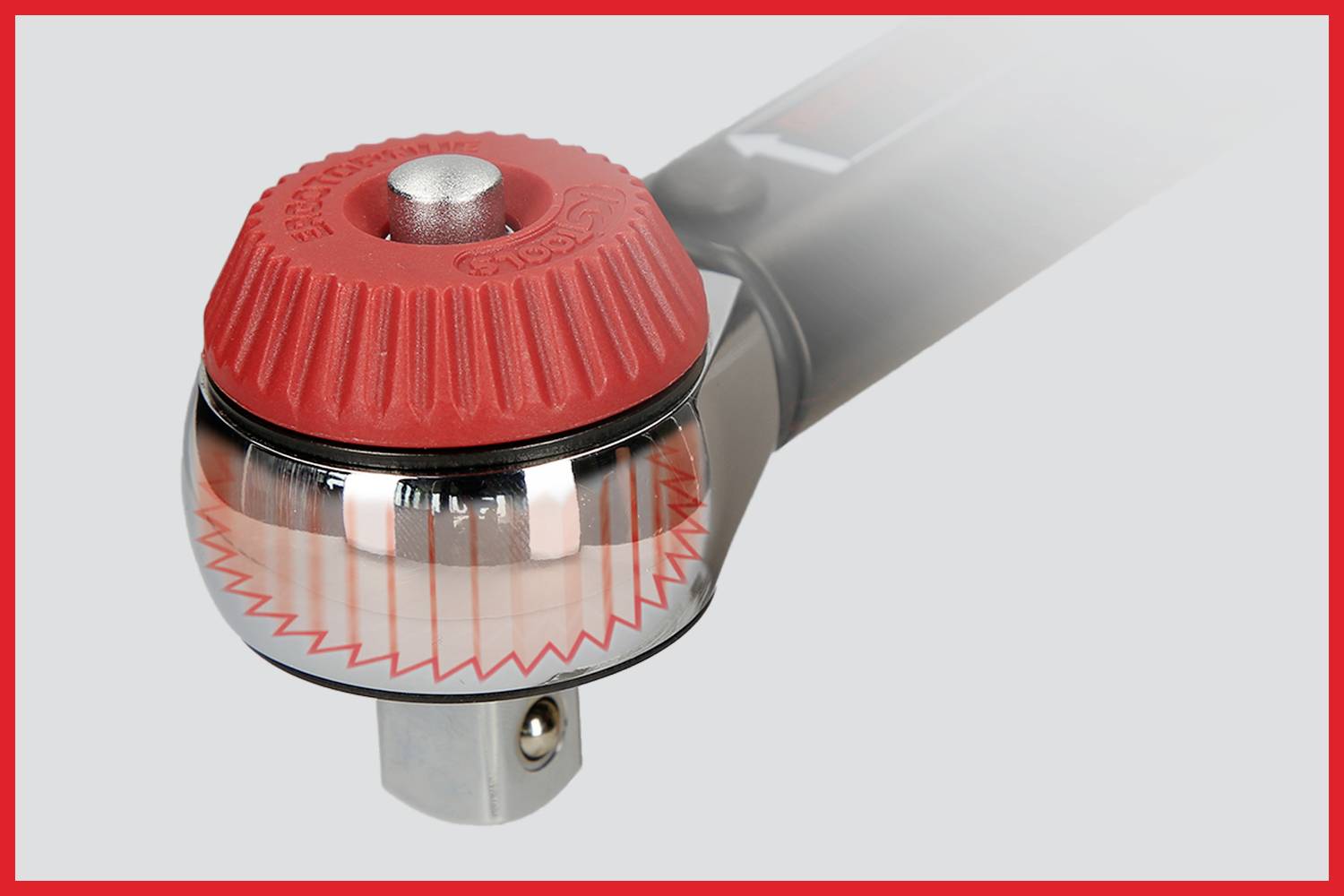 Nahaufnahme eines Drehmomentschlüssels mit rotem Griff und Metallkopf. Der Schlüssel liegt auf einem grauen Hintergrund.