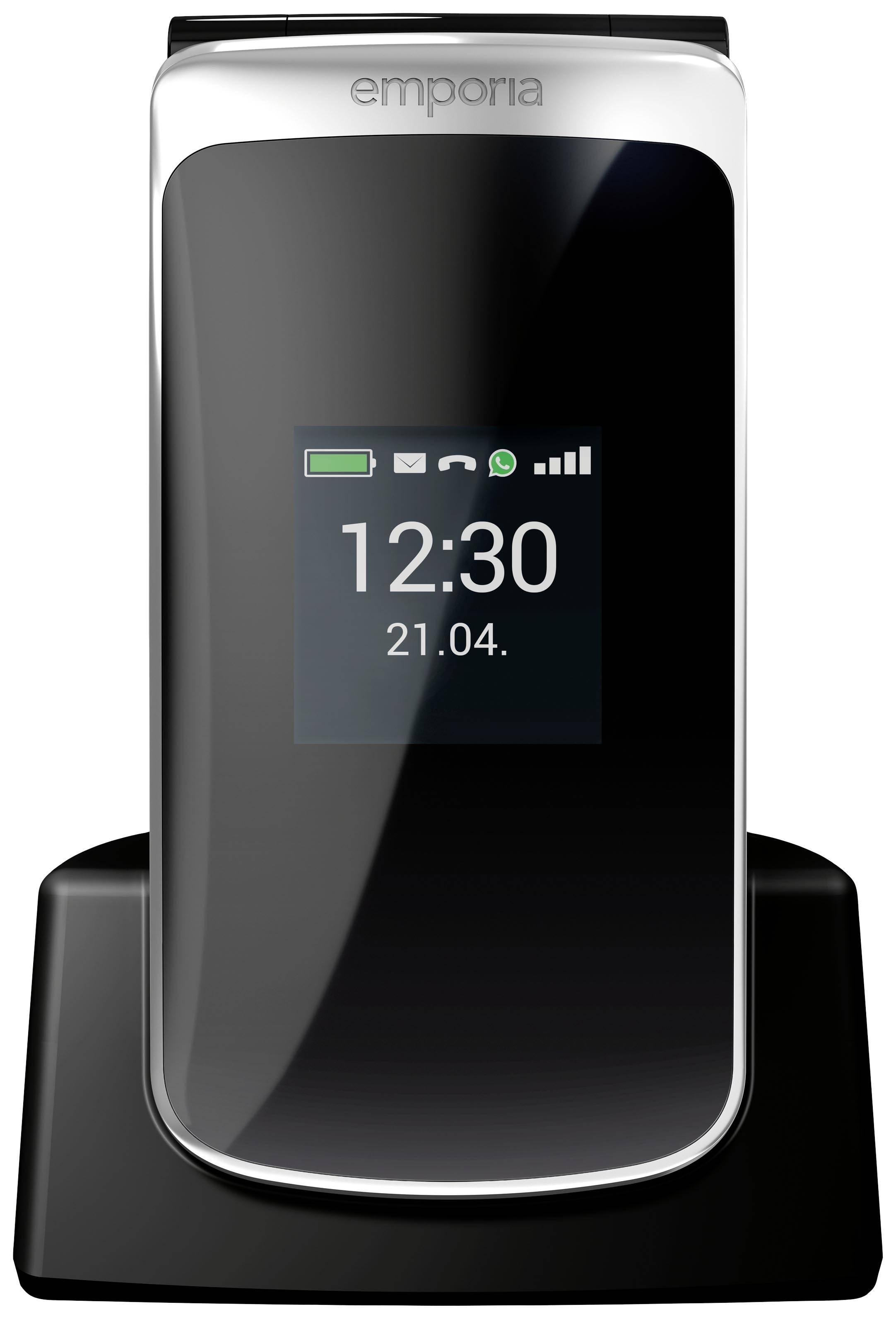 Ein Klapphandy in einer Ladestation zeigt auf dem Display die Uhrzeit '12:30' und das Datum '21.04.' an.