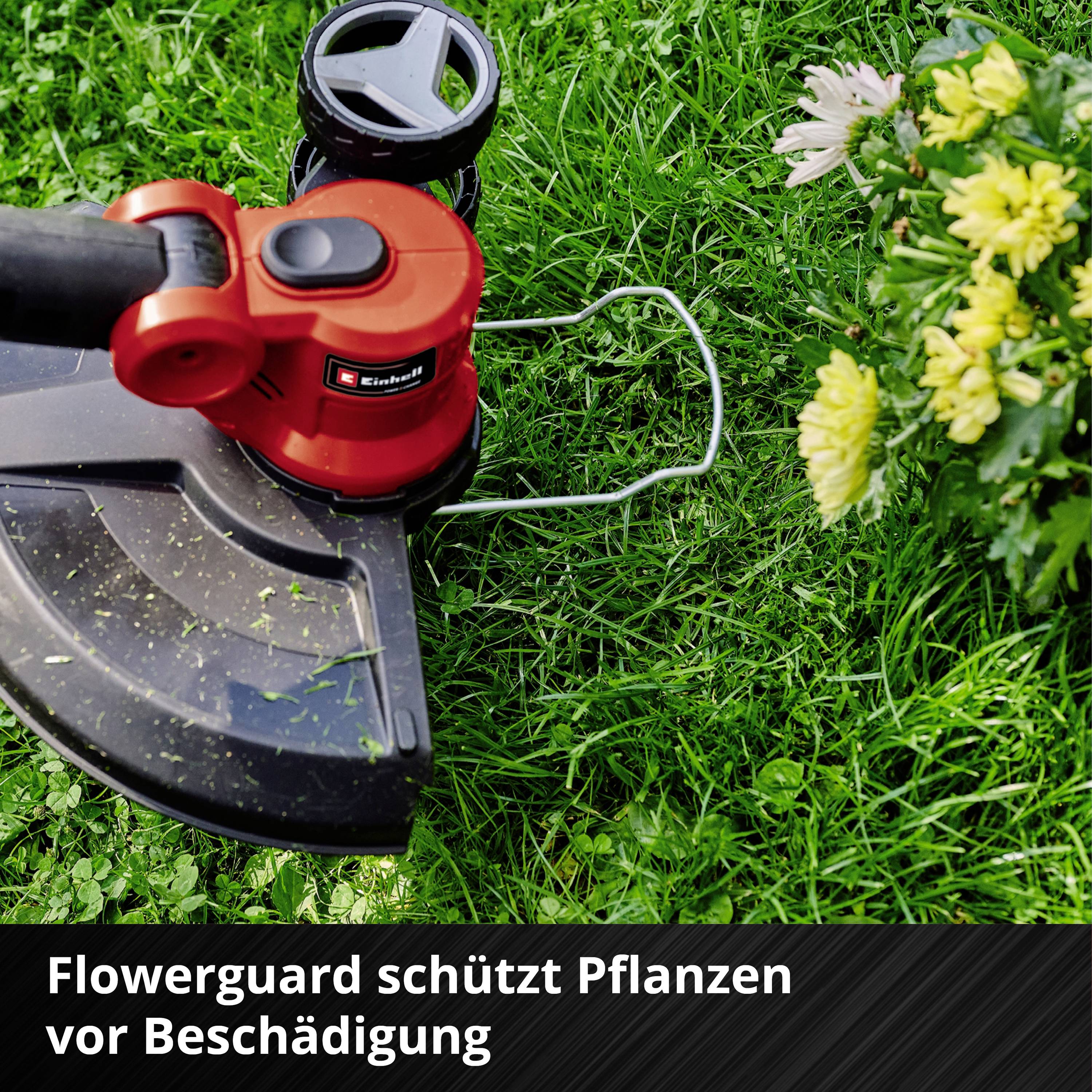 Ein Rasentrimmer mit 'Flowerguard' Schutz arbeitet in einem Garten, umgeben von grünem Gras und gelben Blumen.