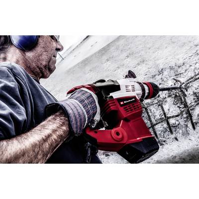 Person mit Gehörschutz arbeitet mit einem Drucklufthammer an einer Betonwand.