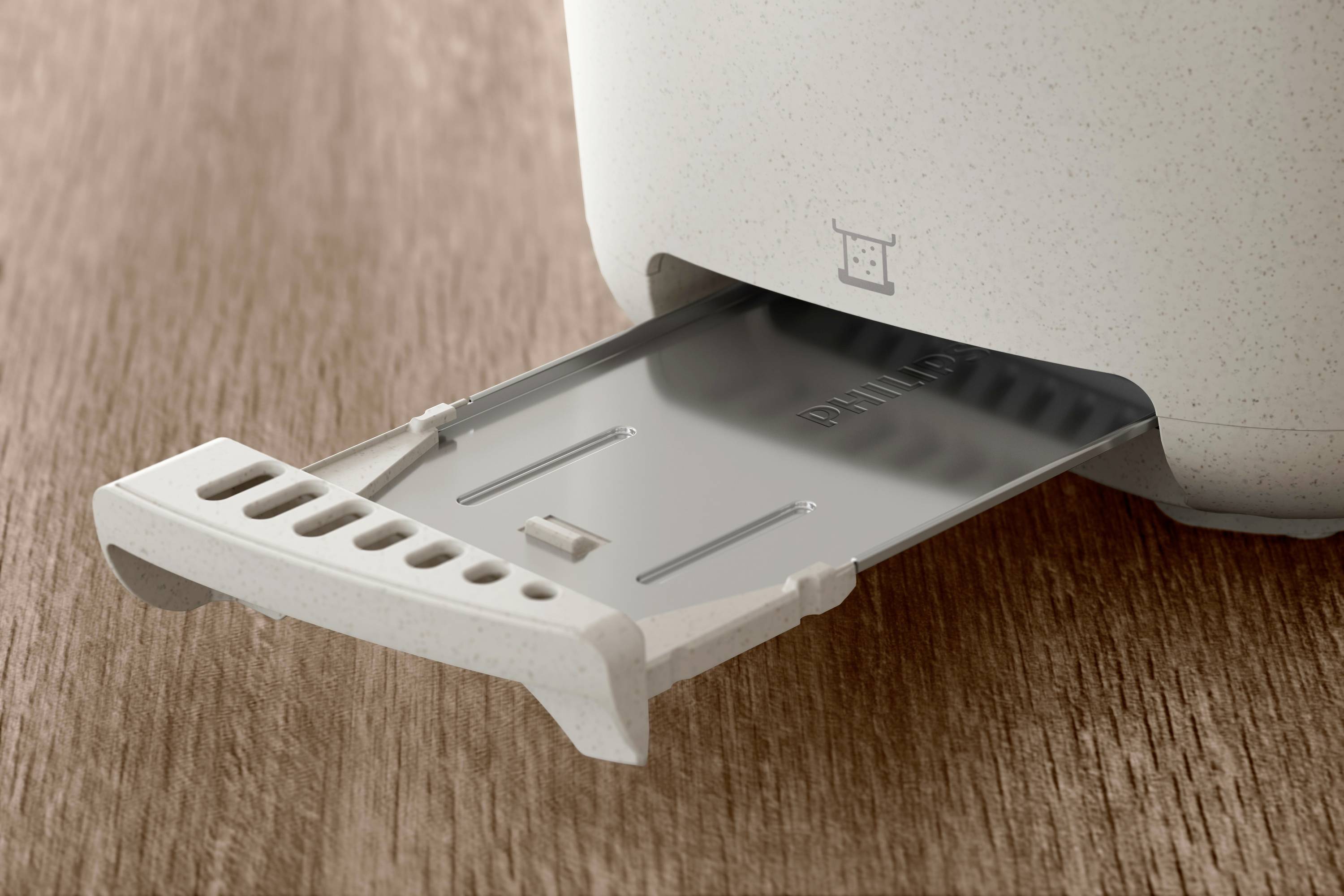 Ein Toaster mit herausgezogener Krümelschublade auf einer Holzoberfläche.