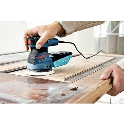 Eine Person schleift mit einem elektrischen Schwingschleifer eine Holzoberfläche. Der Schleifer ist von der Marke Bosch.