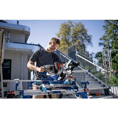 Ein Mann arbeitet im Freien mit einer Kapp- und Gehrungssäge. Er trägt Schutzbrille und Gehörschutz. Im Hintergrund eine Treppe.