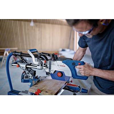 Ein Mann in Werkstatt benutzt eine elektrische Kappsäge, um ein Holzbrett zu schneiden. Die Umgebung wirkt handwerklich und technisch.