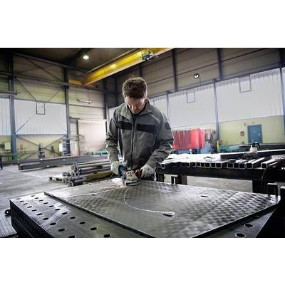 Eine Person schleift eine große Metallplatte in einer Fabrikhalle. Sie tragen Schutzkleidung und arbeiten konzentriert an einem Tisch.