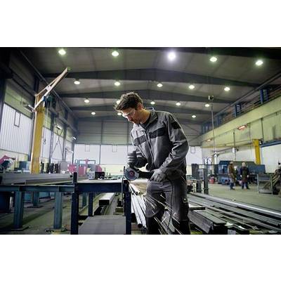 Ein Mann in Arbeitskleidung schneidet mit einem Winkelschleifer Metall in einer Fabrikhalle. Funken sprühen.