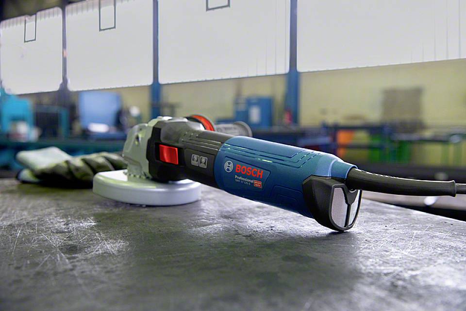 'Elektrischer Winkelschleifer der Marke Bosch auf einer Werkbank in einer Industrieumgebung.'