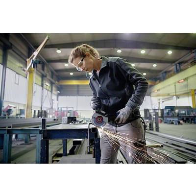 Frau in Arbeitskleidung schleift Metall in einer großen Werkhalle. Funken sprühen vom Werkzeug. Im Hintergrund sind Maschinen zu sehen.
