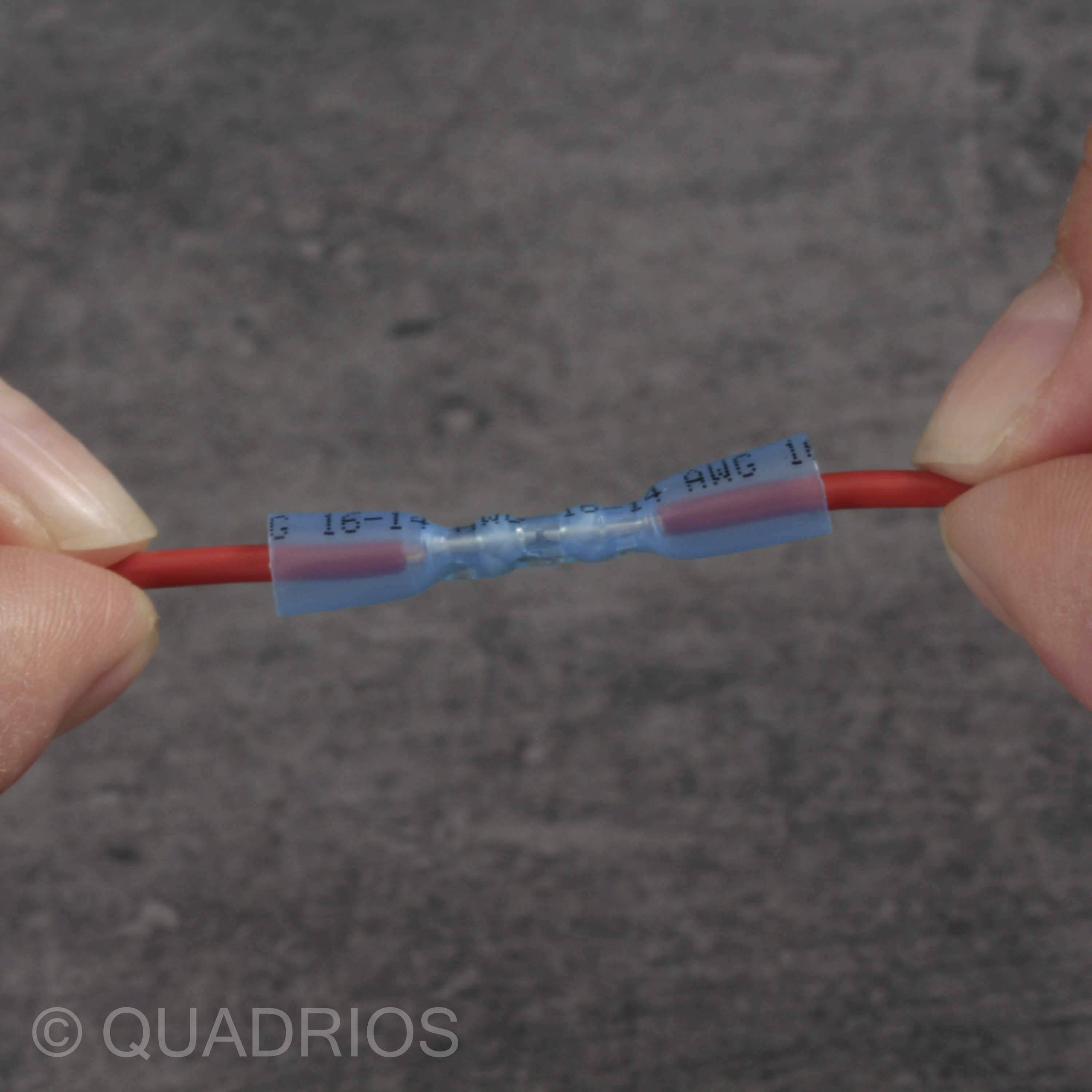 Zwei Hände halten ein isoliertes Kabel mit einer blauen Verbindungshülse auf einem dunklen Hintergrund.