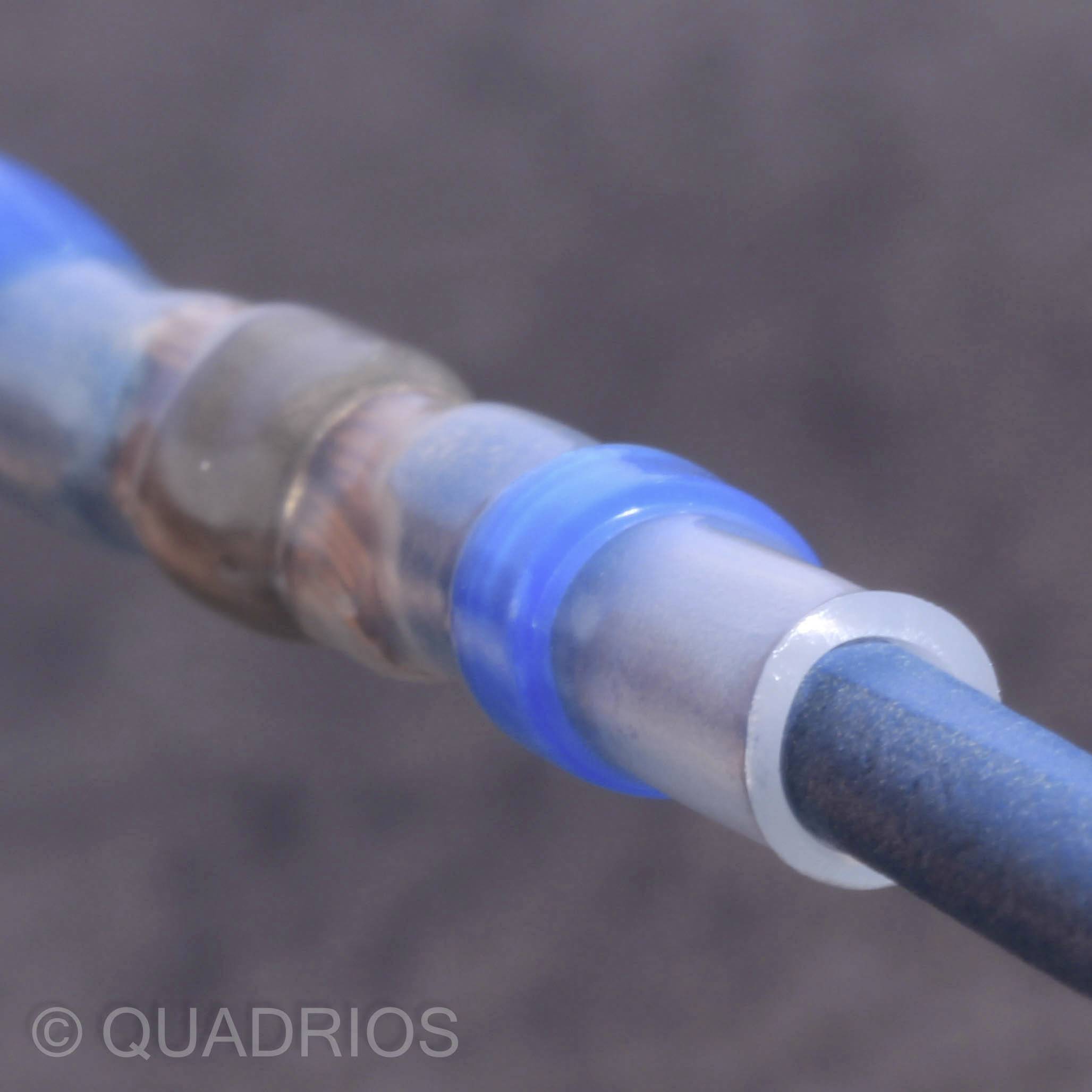 Ein blaues Kabel ist mit Schrumpfschlauch verbunden. Der Hintergrund ist unscharf. Ziel ist die elektrische Isolation und Verbindung.