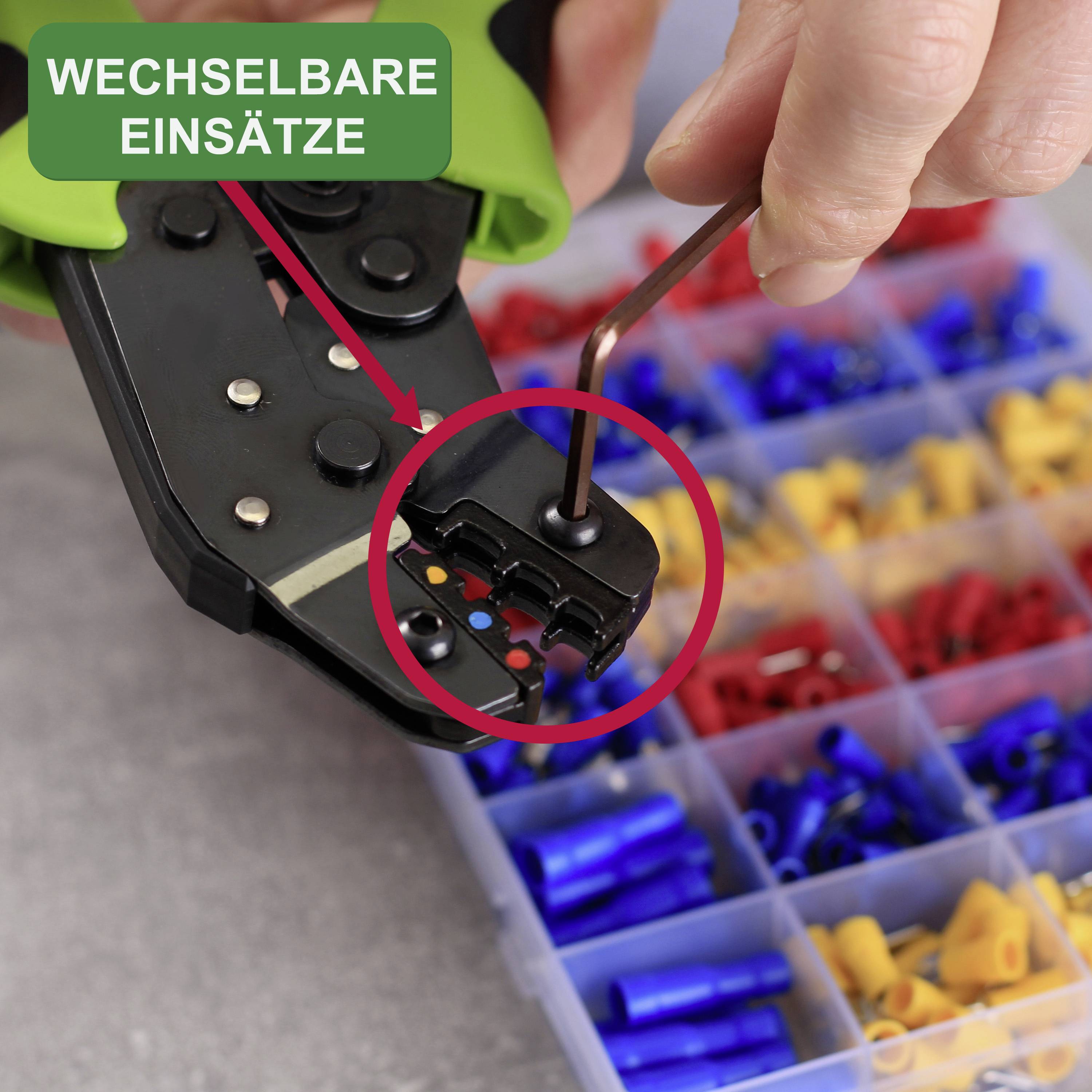 Hand hält Werkzeug zum Crimpen mit gekennzeichneten 'wechselbaren Einsätzen'. Hintergrund zeigt bunte Kabelhülsen in einem Organizer.