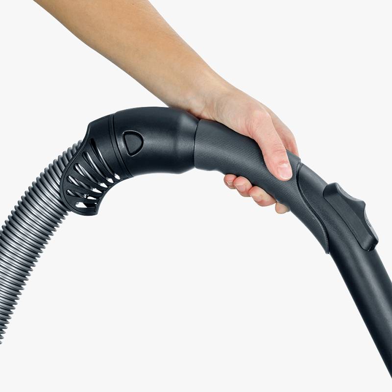 Eine Hand hält den Schlauch eines Staubsaugers.