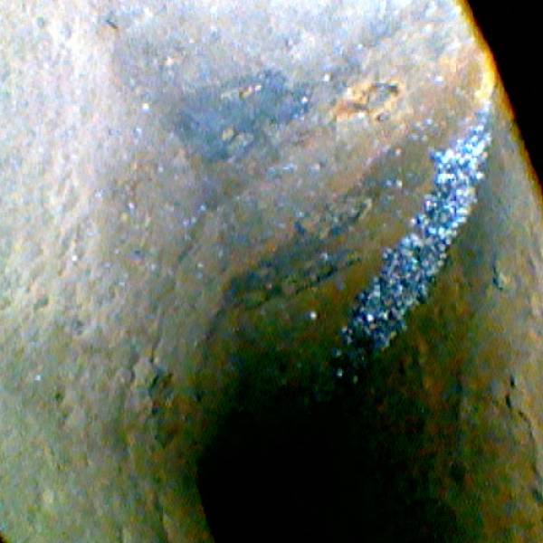 Eine vergrößerte Ansicht eines Felsens mit einem hellen, bläulichen Streifen, der sich diagonal durch das Bild zieht.