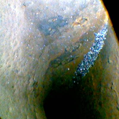 Eine vergrößerte Ansicht eines Felsens mit einem hellen, bläulichen Streifen, der sich diagonal durch das Bild zieht.