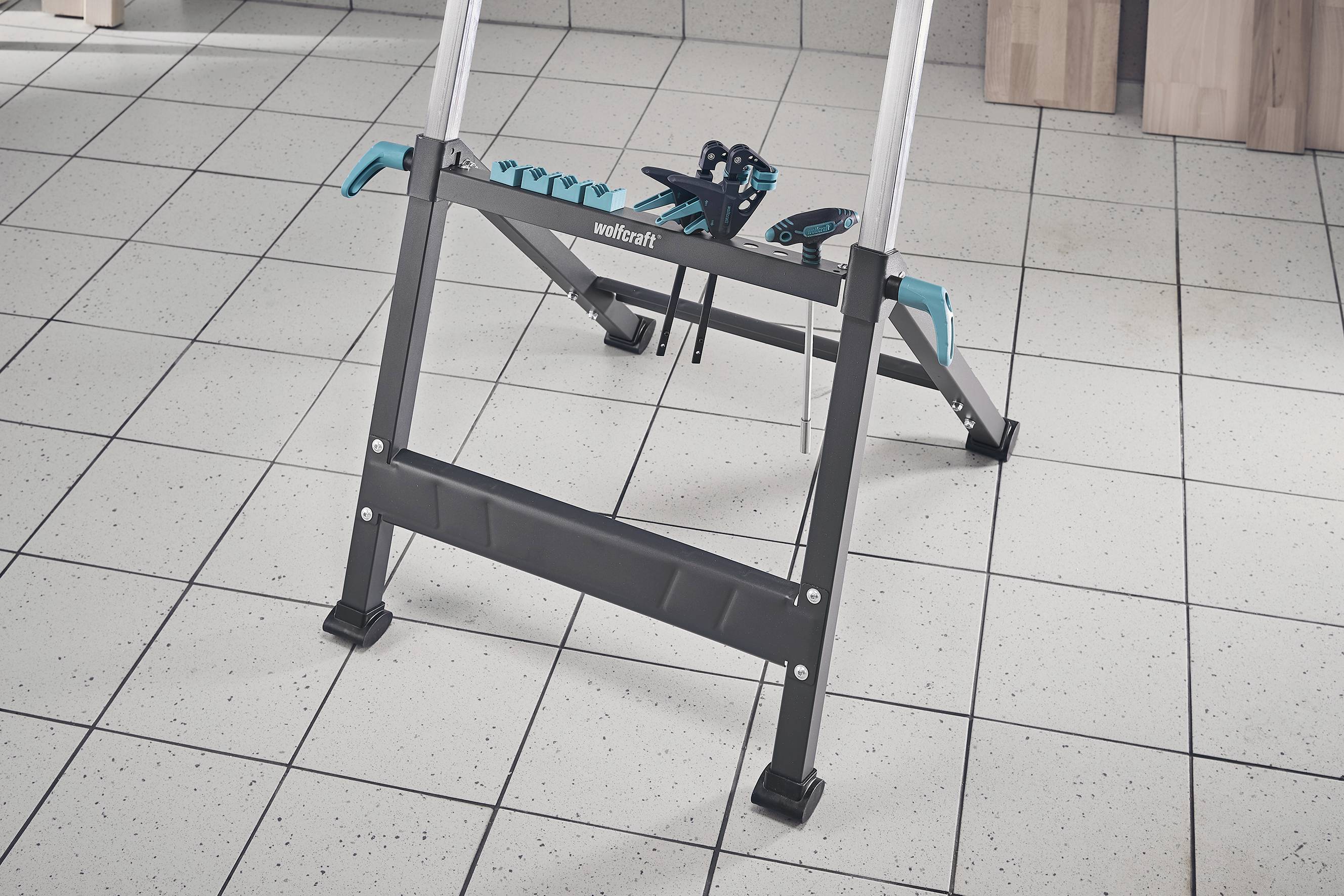 Leiter auf gefliestem Boden stehend, im Hintergrund eine Werkbank mit Werkzeugen.