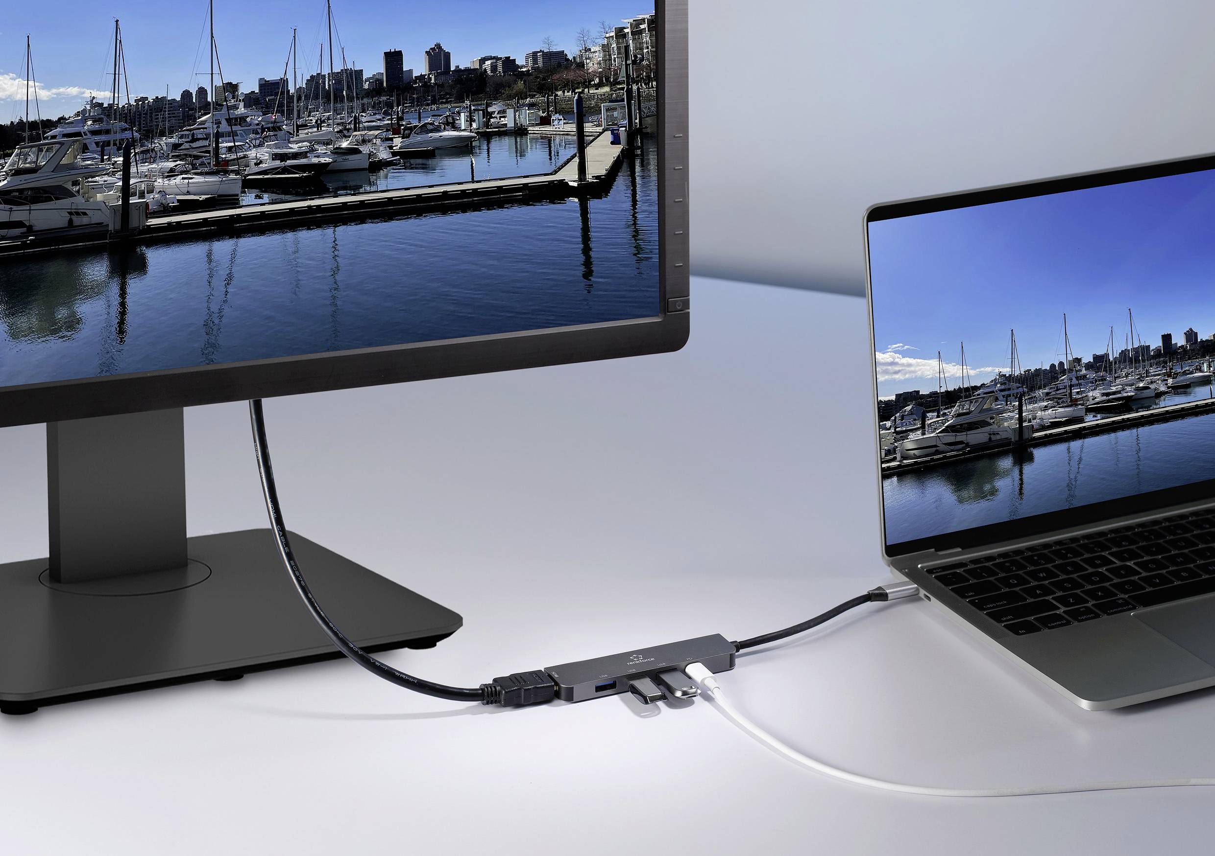 Ein Laptop ist über Kabel mit einem externen Monitor verbunden. Beide Bildschirme zeigen ein identisches Bild eines Yachthafens.