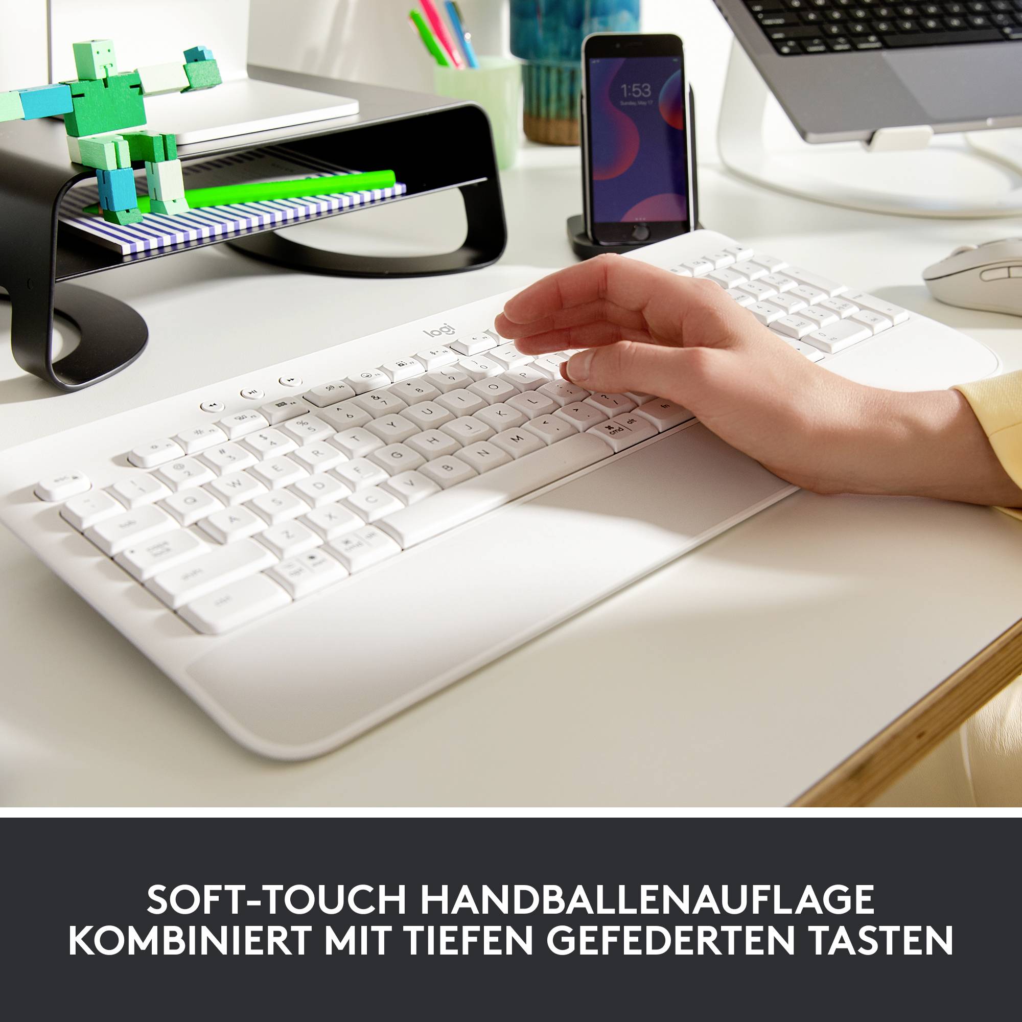 Weiße Tastatur mit Soft-Touch Handballenauflage. Auf einem Monitor wird ein grüner Trabant gezeigt. Ein Smartphone steht daneben.