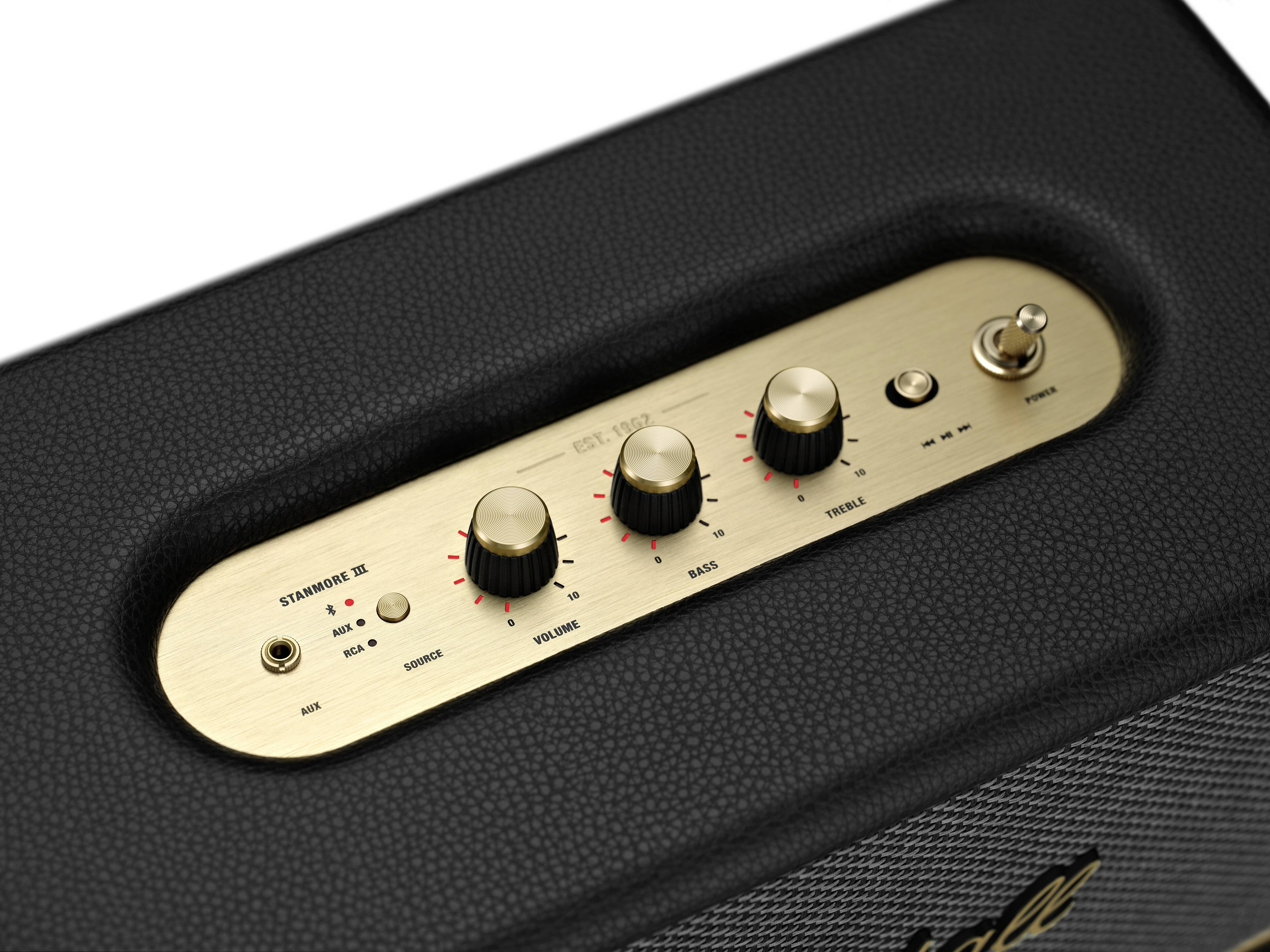 Schwarzer Lautsprecher mit goldener Steuerungsplatte, drei Drehknöpfen für Lautstärke, Bass und Treble, und Kippschalter.