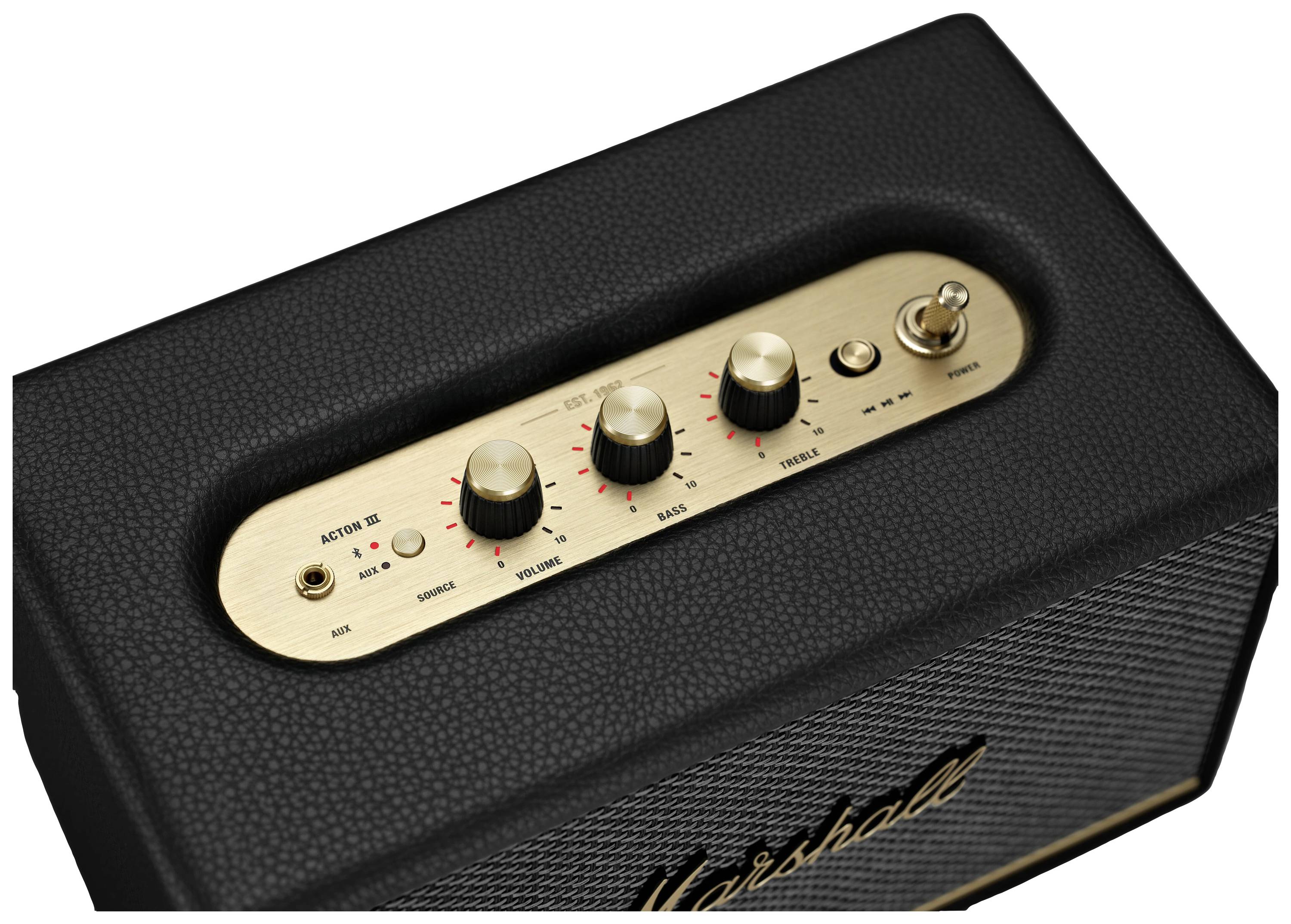 Ein schwarzer Lautsprecher mit goldener Bedienfläche zeigt drei Drehknöpfe für Bass, Treble und Volume sowie Kippschalter für Power.