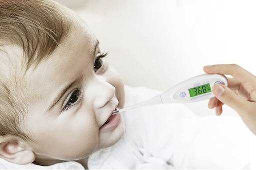 Kleinkind mit einem digitalen Thermometer im Mund, das eine Temperatur von 36,8°C anzeigt. Hand hält das Thermometer.