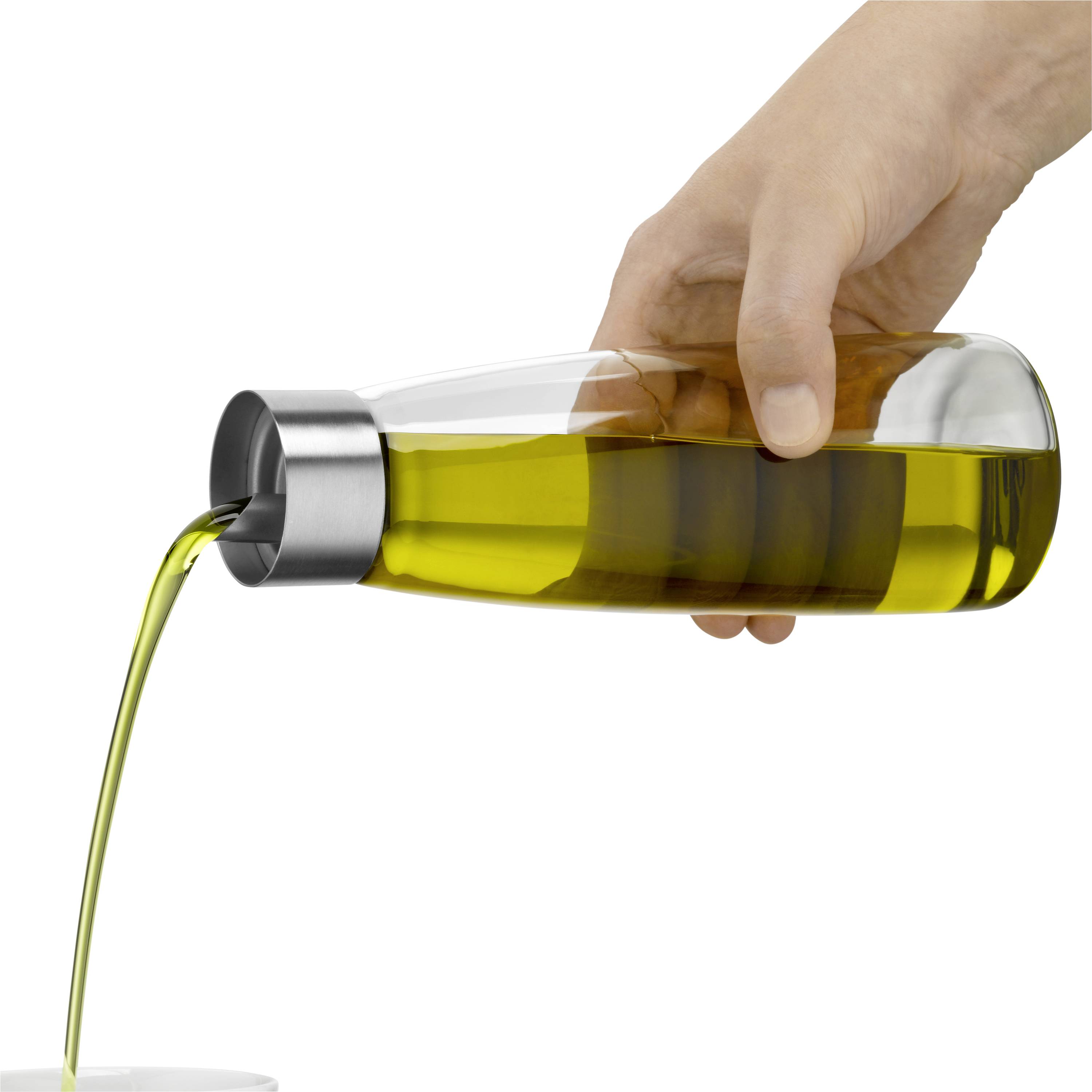 Eine Hand gießt Öl aus einer transparenten Karaffe mit silbernem Ausgießer.