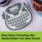 Ein Etikettendrucker neben Tellern mit gestapelten Keksen. Text auf Papier: 'Eine klare Vorschau der Nachrichten vor dem Druck'.