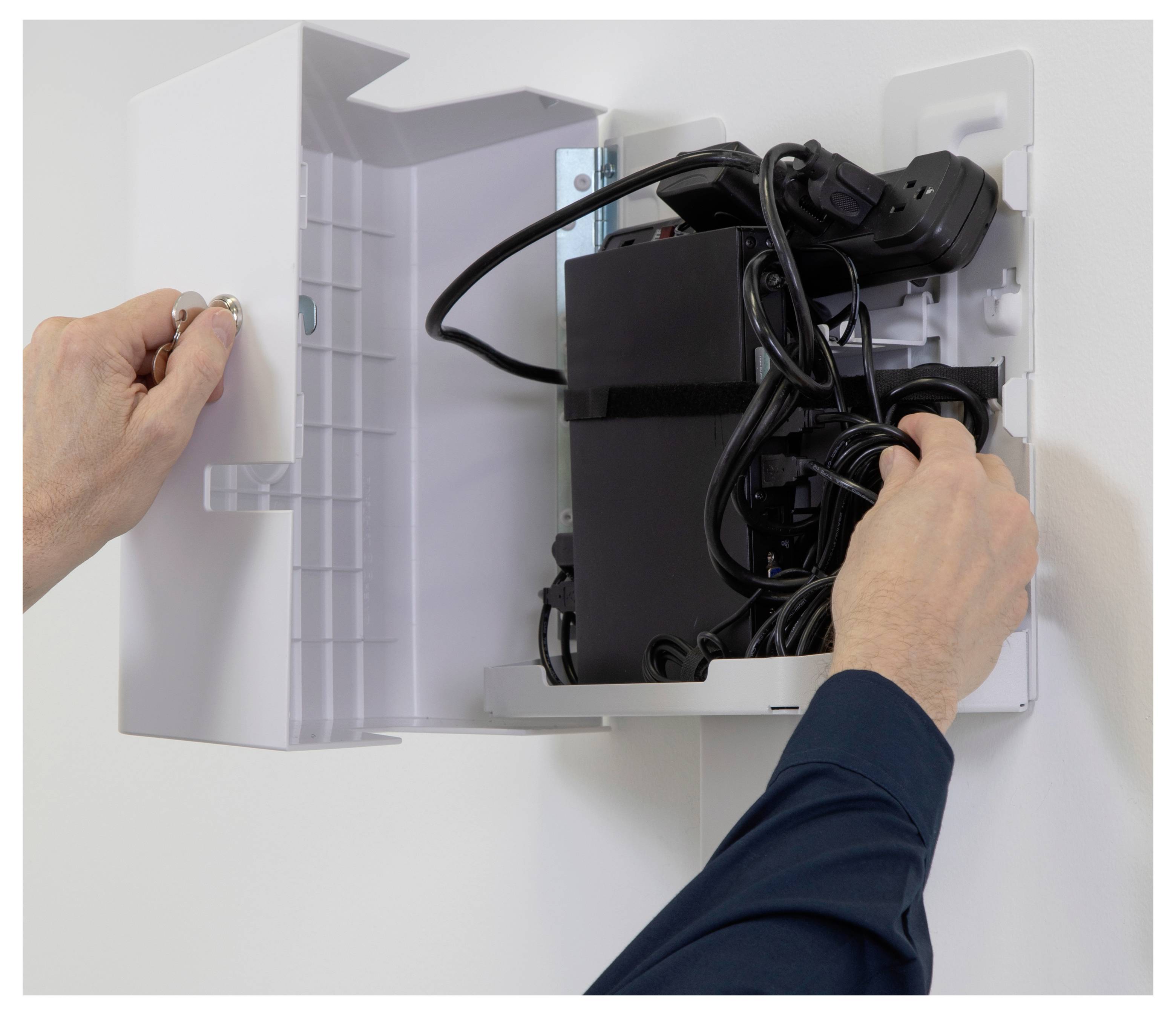 „Hände schließen einen weißen Wandschrank, der elektronische Geräte und Kabel enthält, und organisieren die Ausrüstung sicher."