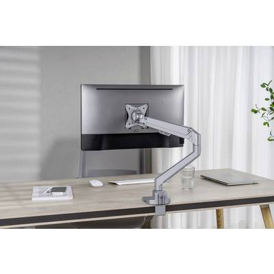 Ein Schreibtisch mit einem Monitor auf einem verstellbaren Arm, eine Tastatur, ein Glas Wasser, ein Laptop und ein Buch mit Smartphone liegen darauf.