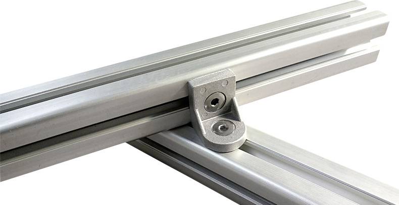 Ein Aluminiumprofil verbindet sich rechtwinklig mit einem anderen Profil durch einen silbernen Eckverbinder.
