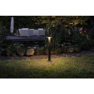 Beleuchteter Garten mit Teich, Felsen und Gräsern; im Hintergrund Gartenmöbel und Bäume, die eine gemütliche Abendstimmung erzeugen.