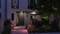 Ein modernes Gebäude bei Nacht mit beleuchtetem Eingang und Hausnummer 21, umgeben von Pflanzen und dezentem Gartenlicht.