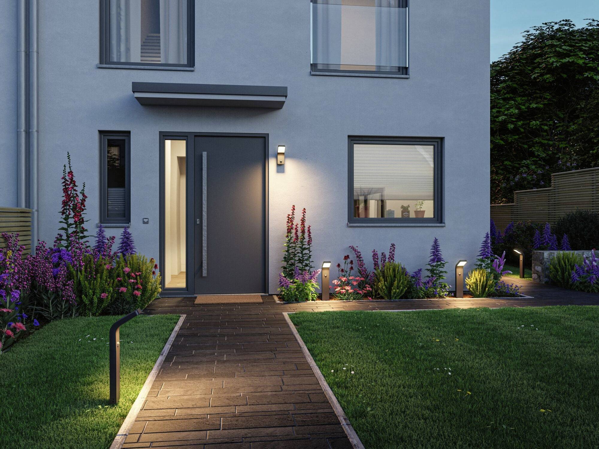 Ein modernes Einfamilienhaus bei Dämmerung, mit beleuchtetem Eingang und gepflegtem Garten.