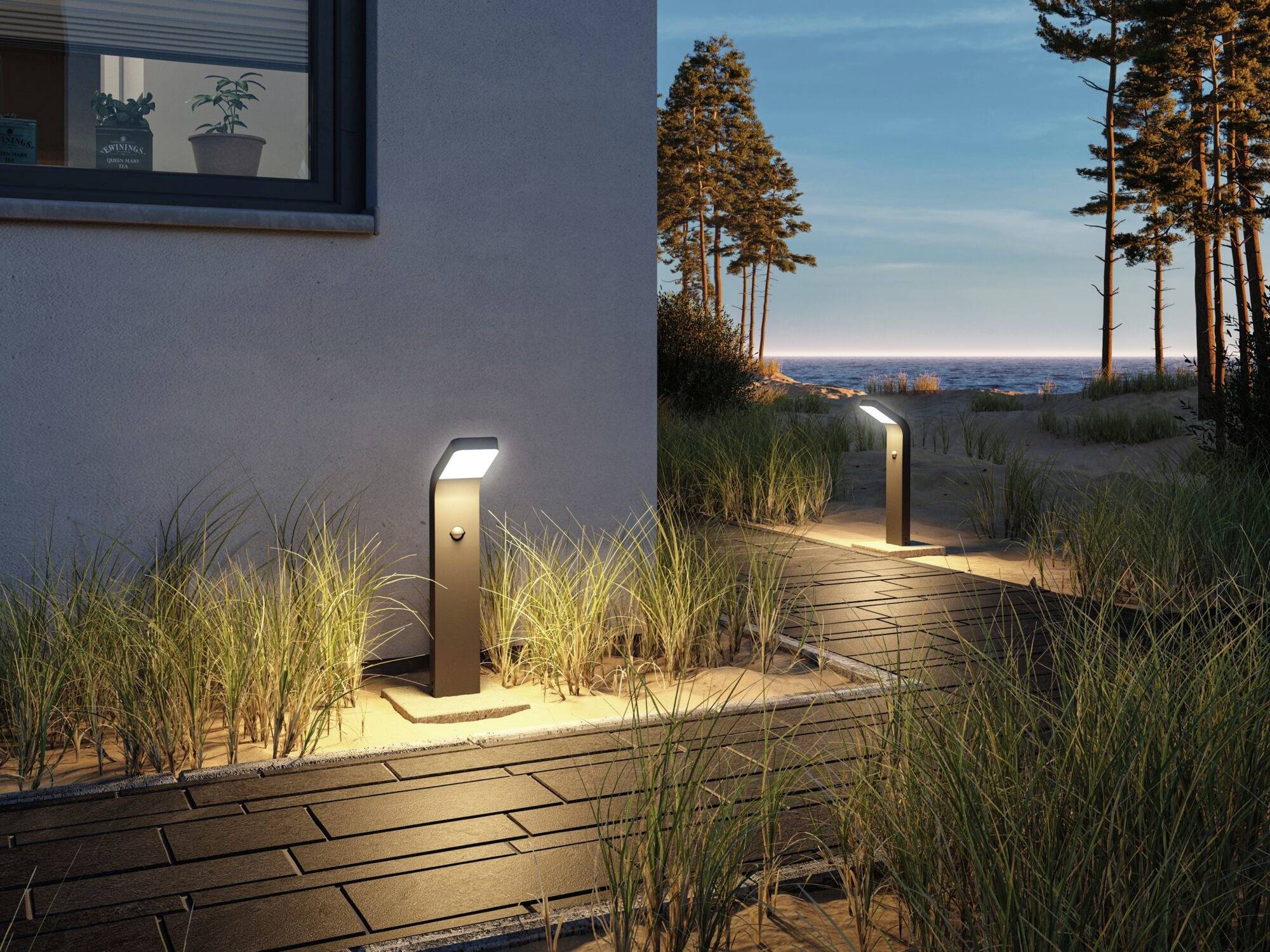 Gartenweg bei Sonnenuntergang, gesäumt von Gras und beleuchtet durch minimalistische Lampen. Hauswand links, Bäume im Hintergrund.