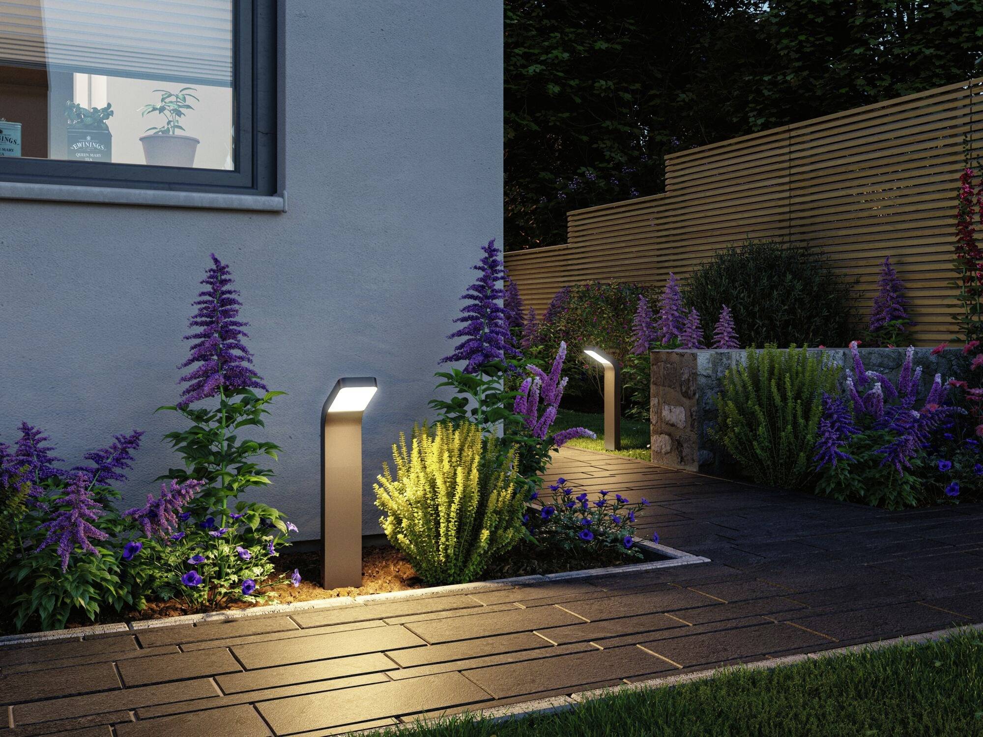 Gartenweg bei Dämmerung mit beleuchteten LED-Leuchten, flankiert von lila und gelben Blumen, neben einem modernen Haus.