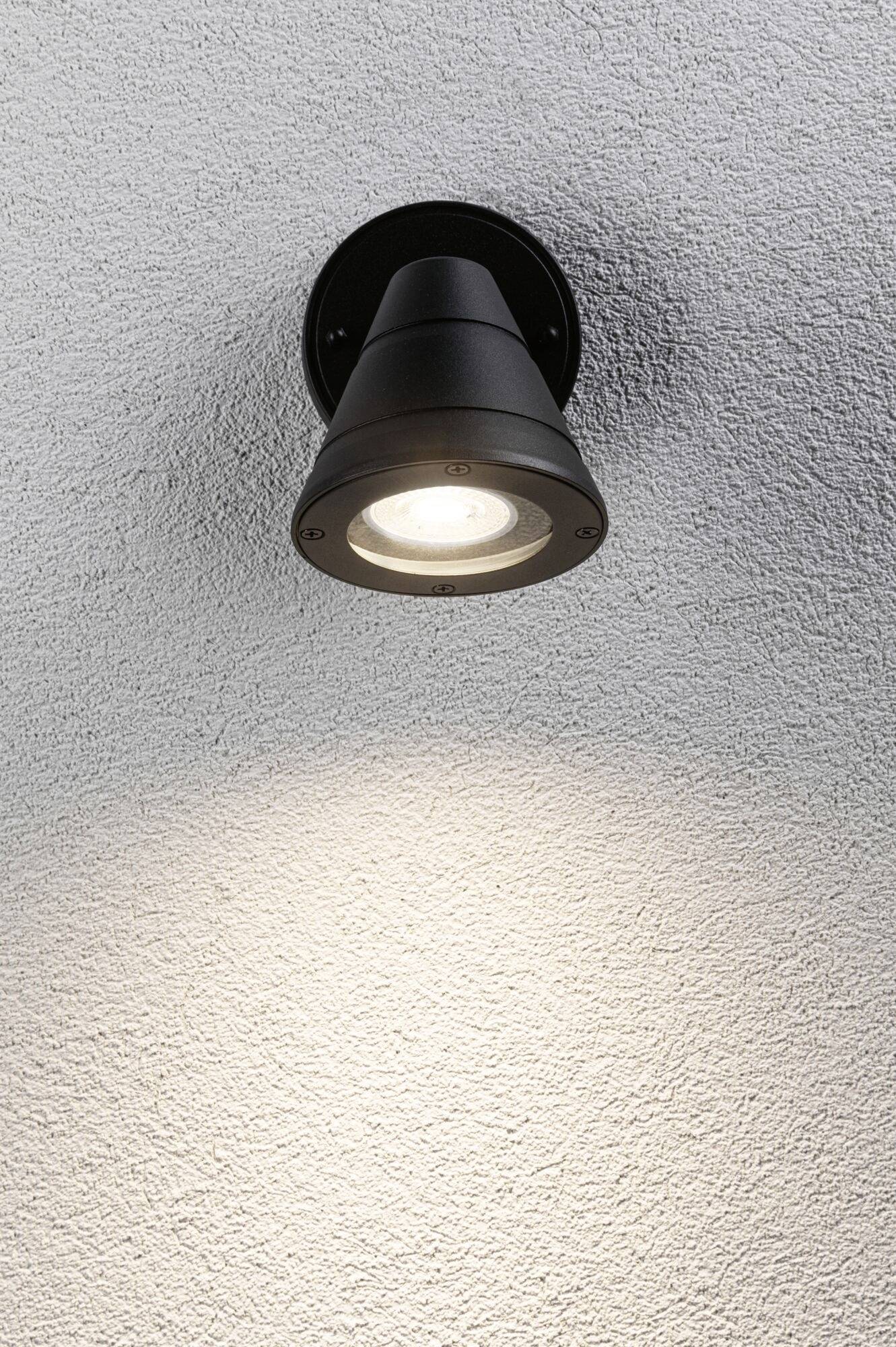Schwarze Wandleuchte an grauer Wand, strahlt Licht nach unten. Ideal für stimmungsvolle Außen- oder Innenbeleuchtung.