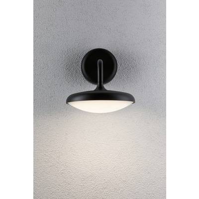 Schwarze Wandlampe leuchtet weiches, warmes Licht auf eine graue Wand, erzeugt eine gemütliche Atmosphäre.