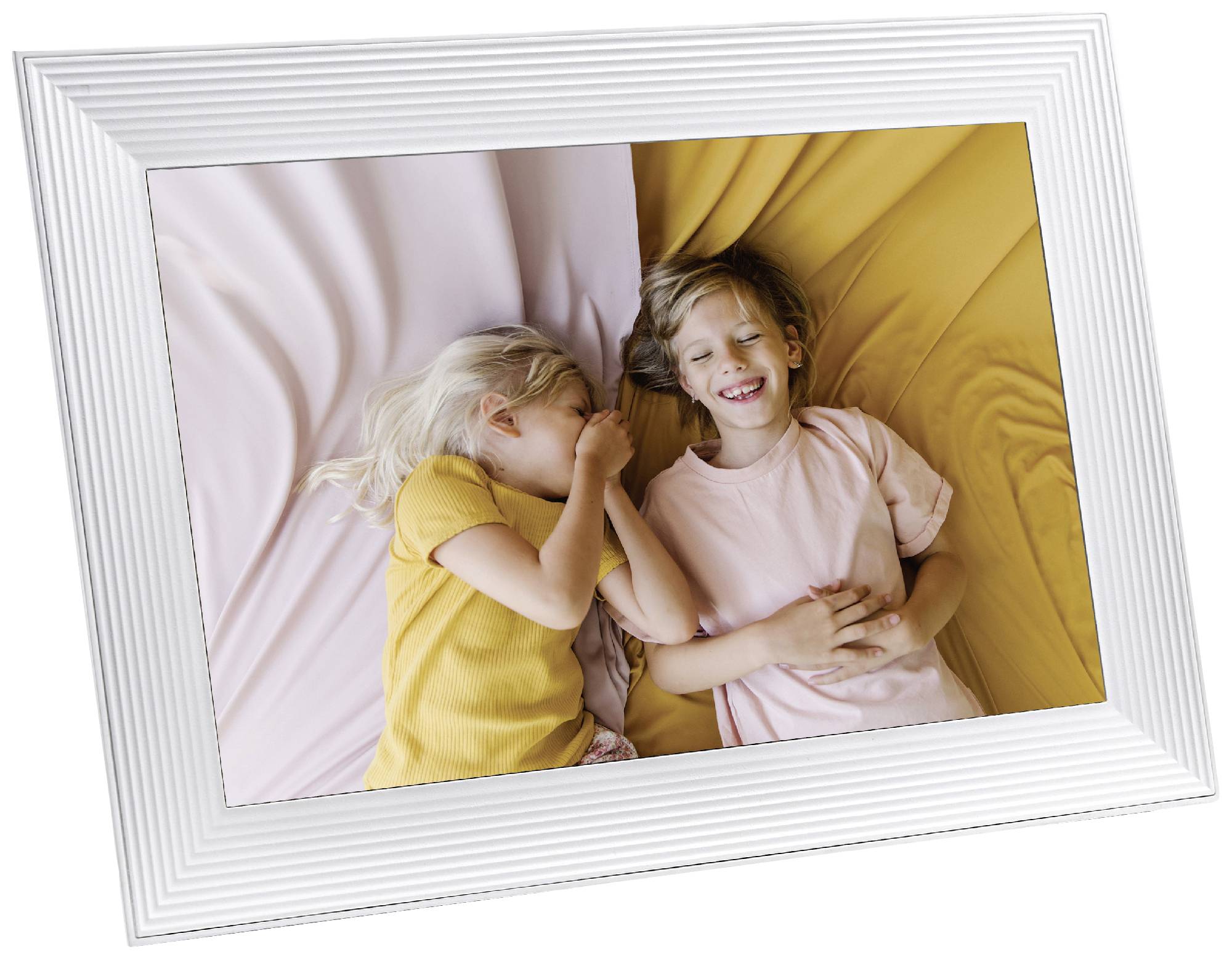 Zwei lachende Kinder liegen auf einem Bett, eines trägt ein gelbes, das andere ein rosa T-Shirt. Sie wirken fröhlich und entspannt.