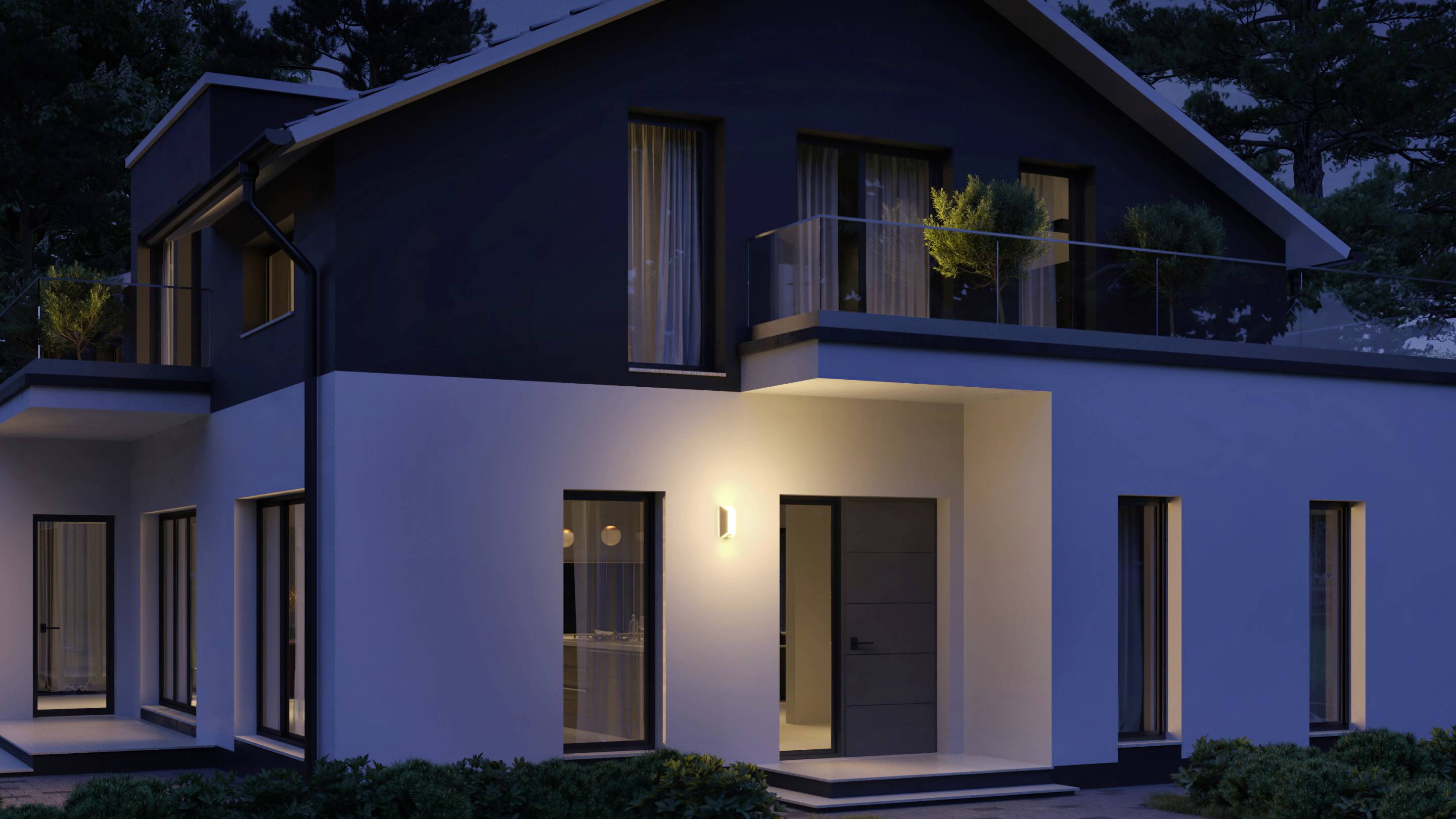 Ein modernes, zweistöckiges Haus bei Nacht. Außenbeleuchtung betont weiße und dunkle Fassaden. Bäume im Hintergrund.