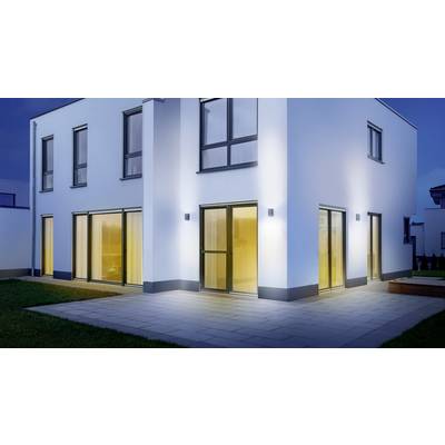 Modernes zweistöckiges Haus bei Nacht mit großen Fenstern, die warmes Licht ausstrahlen. Außenbeleuchtung hebt die Fassade hervor.