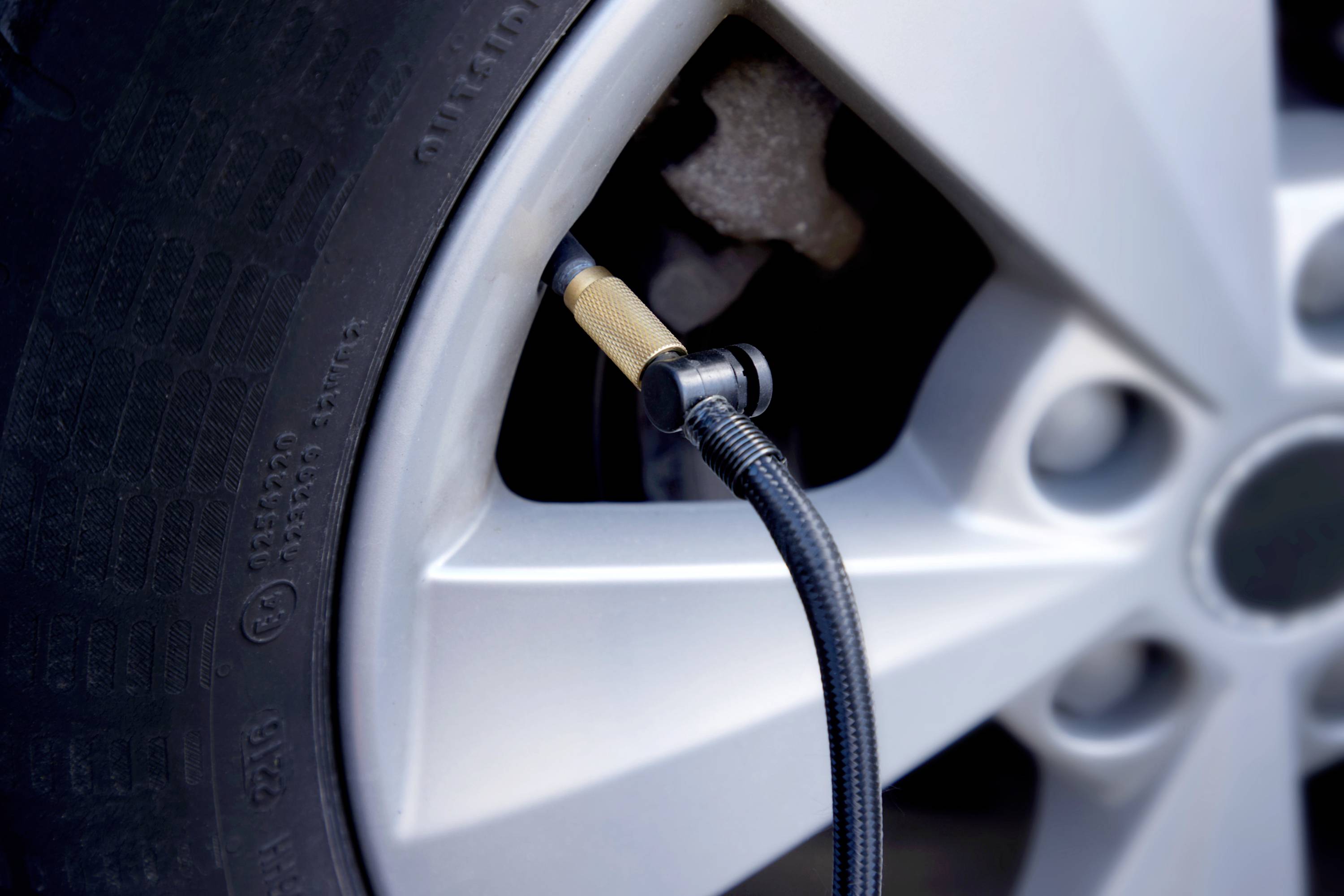 Nahaufnahme eines Autoreifens, an den ein Schlauch angeschlossen ist. Der Schlauch wird möglicherweise zum Aufpumpen des Reifens verwendet.