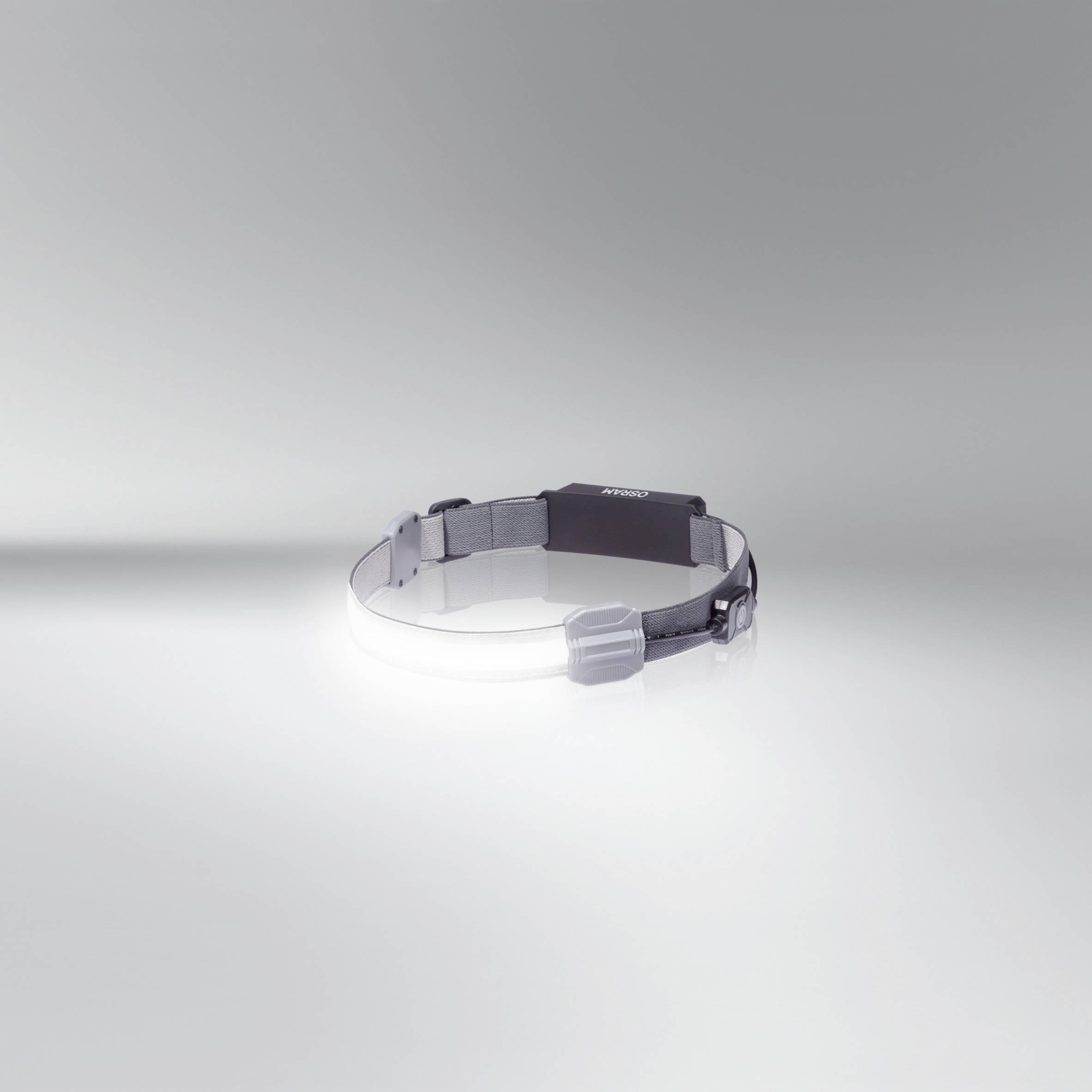Ein schwarzes Stirnband mit grauen Kunststoffelementen auf weißem Hintergrund, möglicherweise ein tragbares Gerät oder Zubehör.