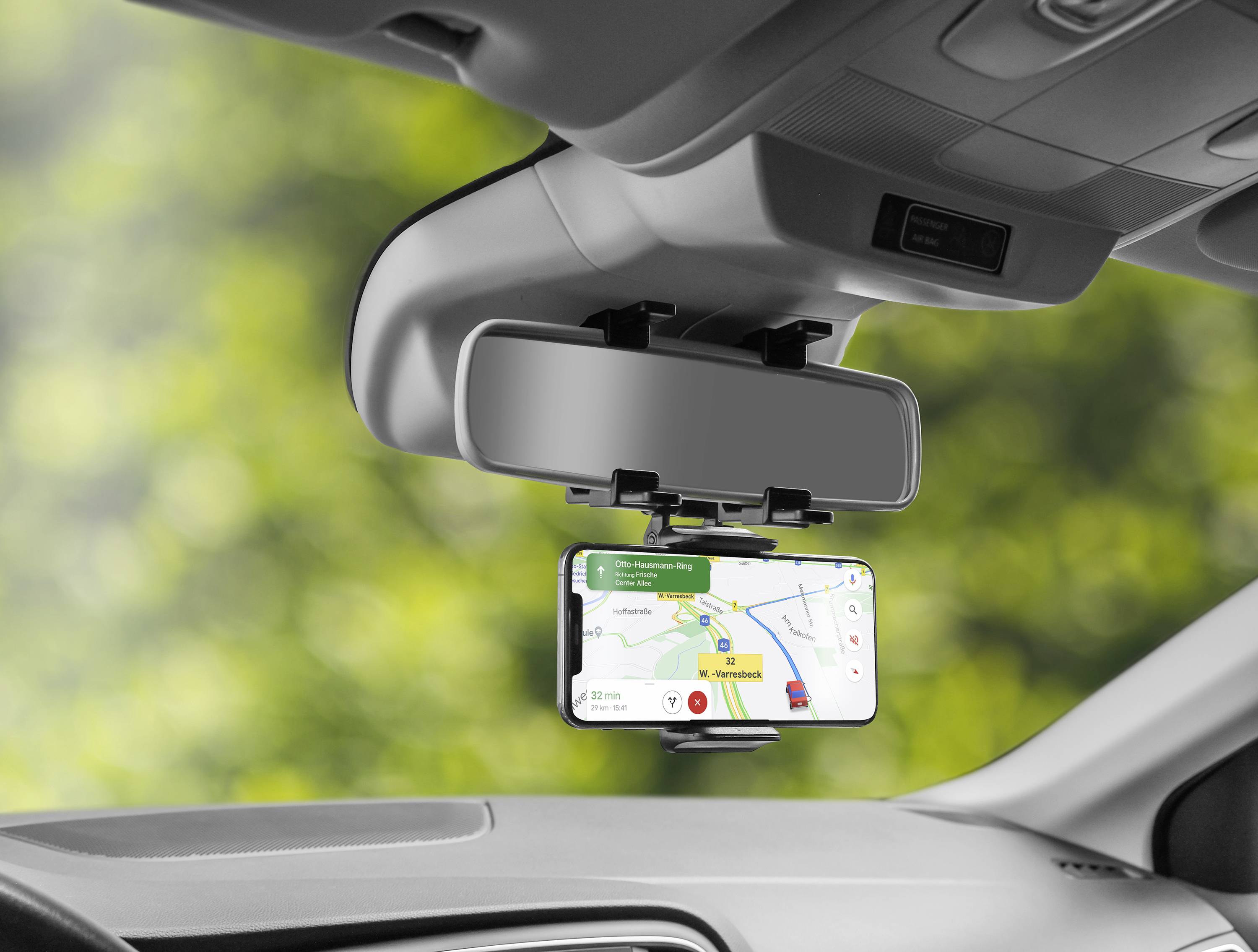 Smartphone an der Auto-Rückspiegelhalterung zeigt eine Navigationsanwendung mit Karte und Route. Sicht aus Fahrersitz.