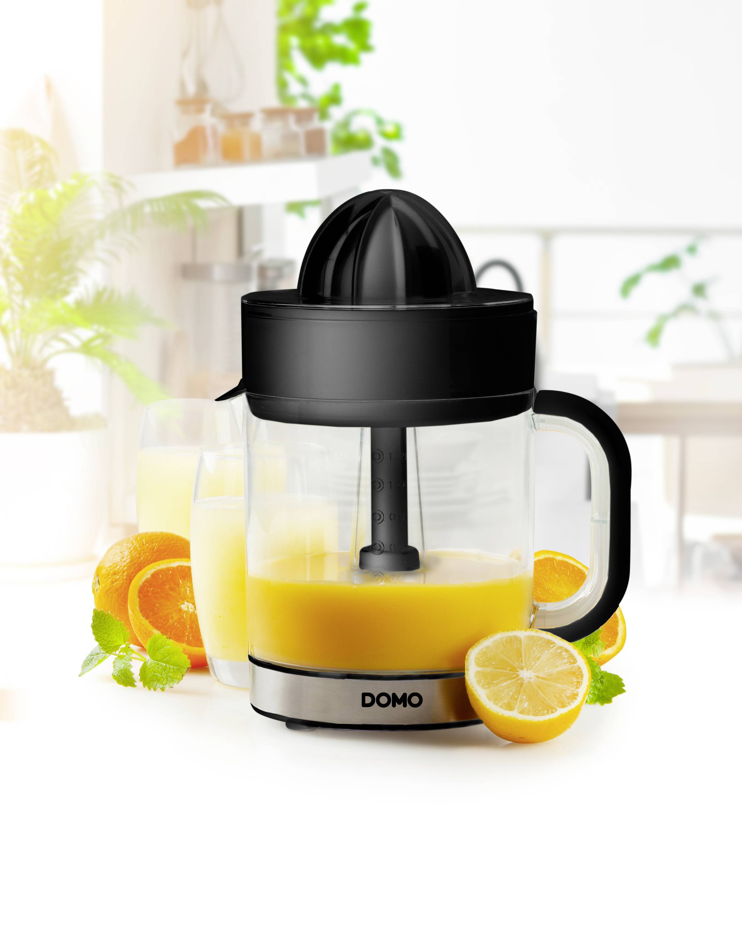 'Elektrische Zitruspresse auf einem Tisch, umgeben von Orangen und Zitronen, mit einem Glas frischem Saft im Hintergrund.'
