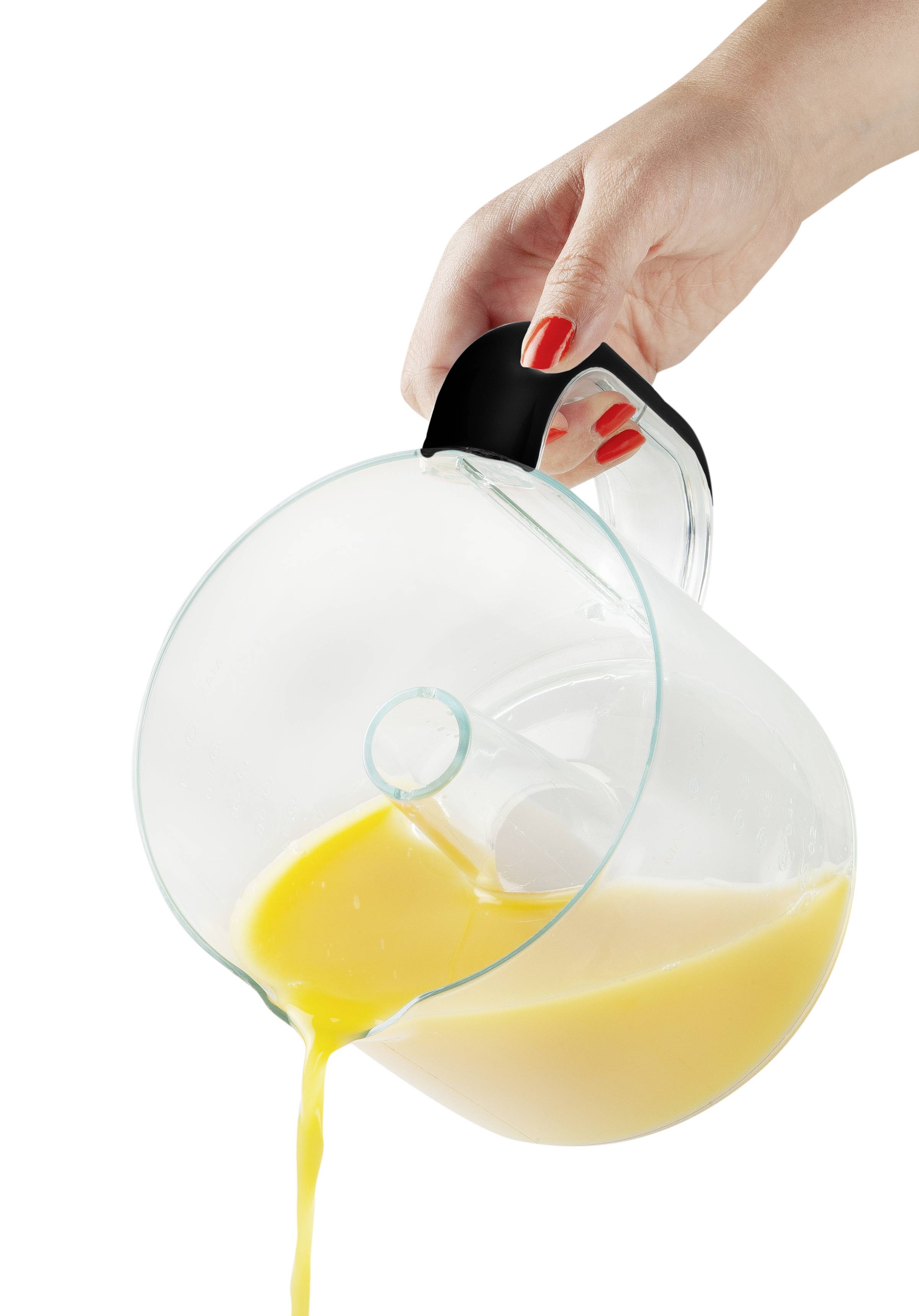 Eine Hand gießt Orangensaft aus einem transparenten Krug.