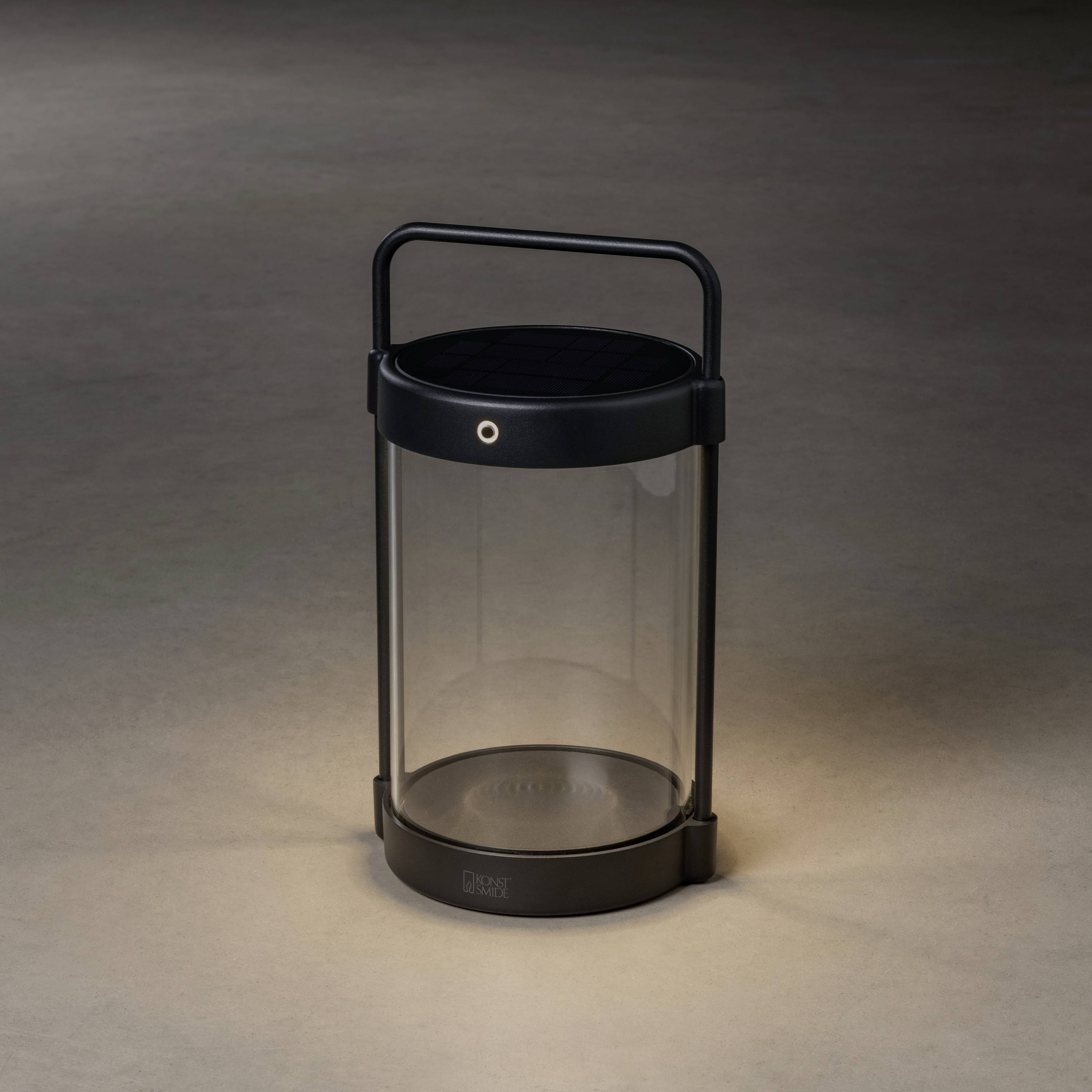 Ein tragbares, rundes LED-Licht mit Griff auf einem dunklen Hintergrund, beleuchtet den Boden darunter. Ideal für Outdoor-Aktivitäten.