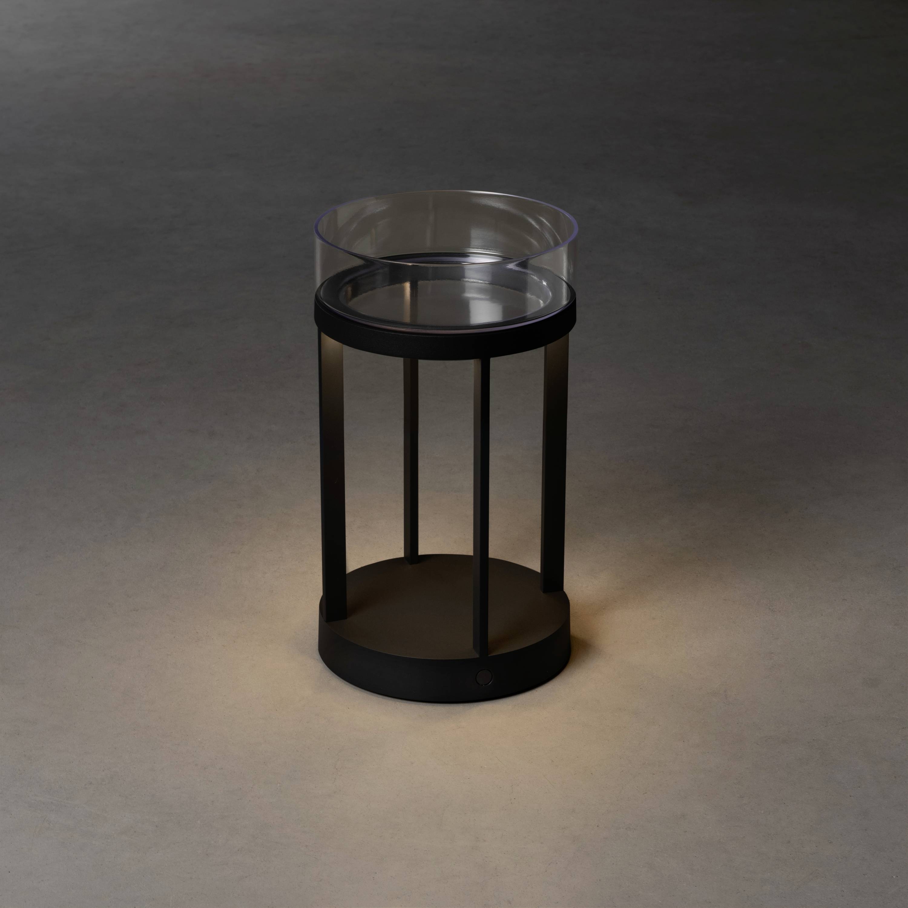 Ein moderner, runder Beistelltisch aus dunklem Metall mit transparentem Glas. Ideal für Wohnbereiche mit minimalistischer Einrichtung.