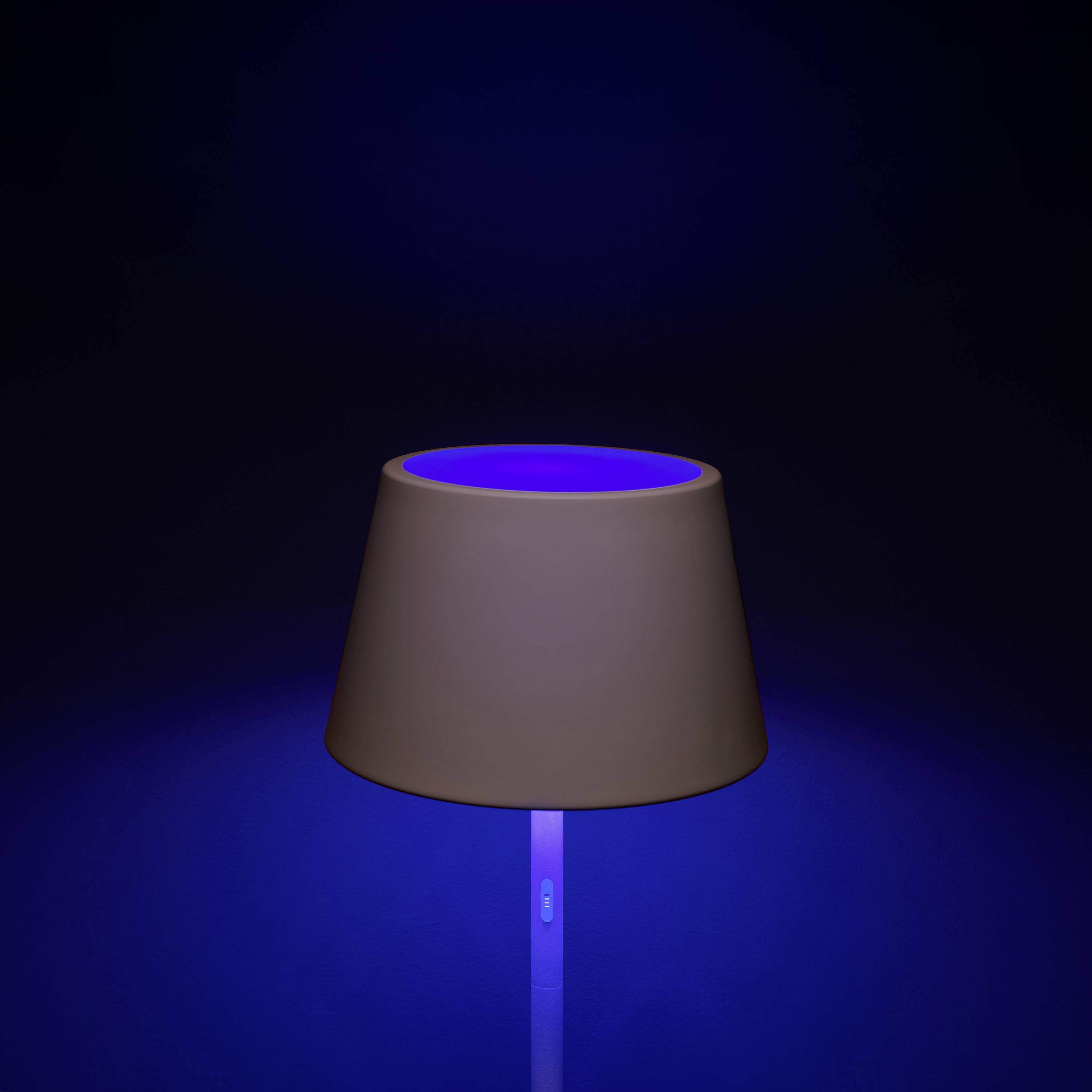 Eine Lampe mit braunem Schirm leuchtet in blauem Licht auf einem dunklen Hintergrund.