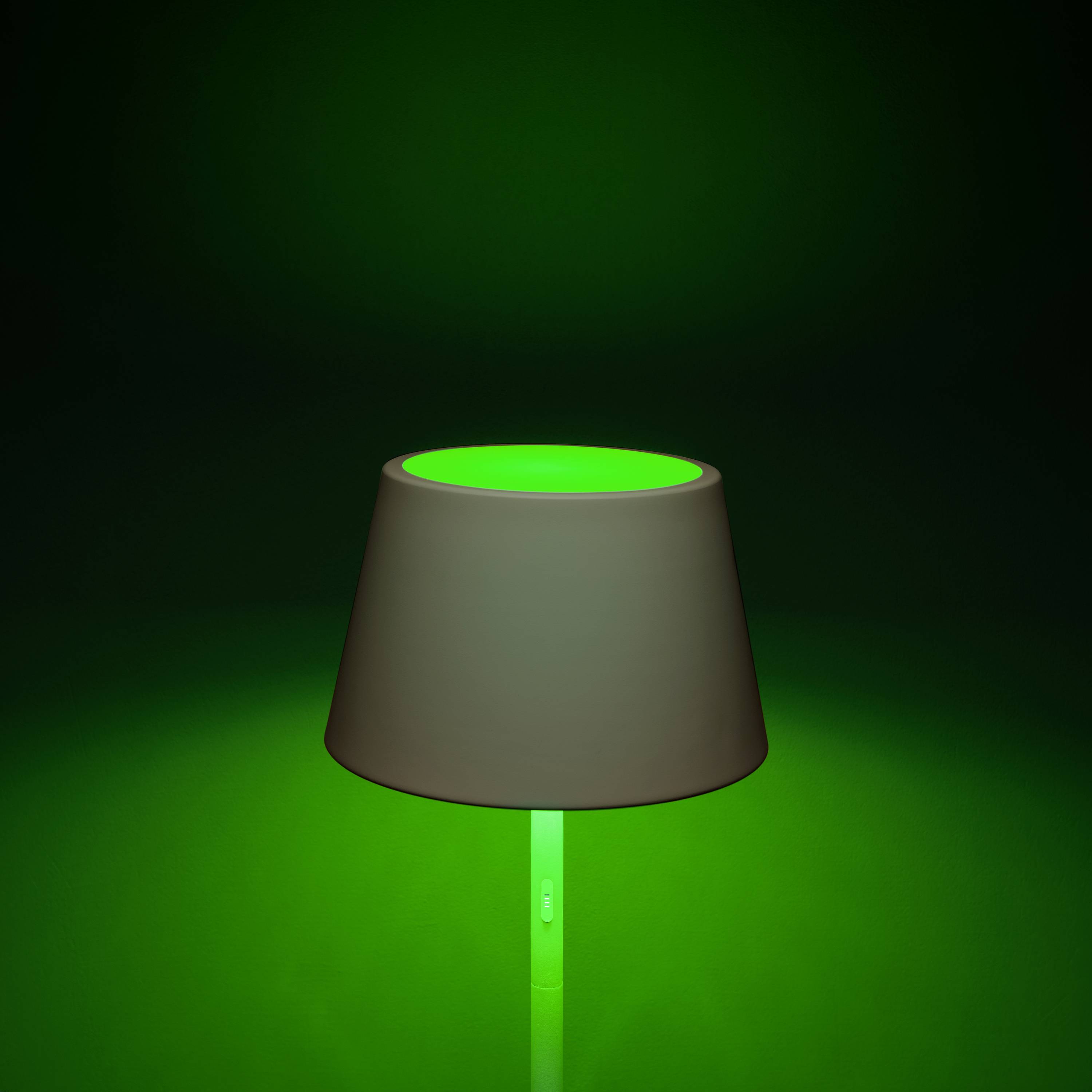 Eine Lampe mit grünem Leuchten steht vor einem dunklen Hintergrund. Sie strahlt ein sanftes Licht aus, das nach oben gerichtet ist.